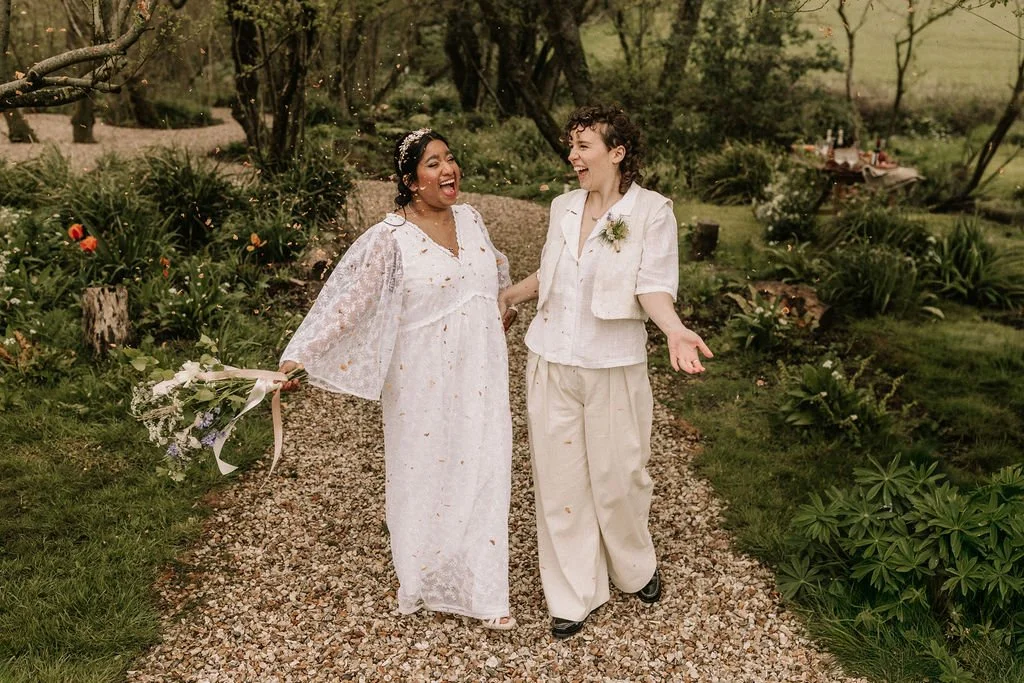 A smiling couple outside, surrounded by greenery, at their wedding styled by Wild Soul Weddings, eco wedding planners in the UK. Sarah Grace Photography. Dominic Williams Photography