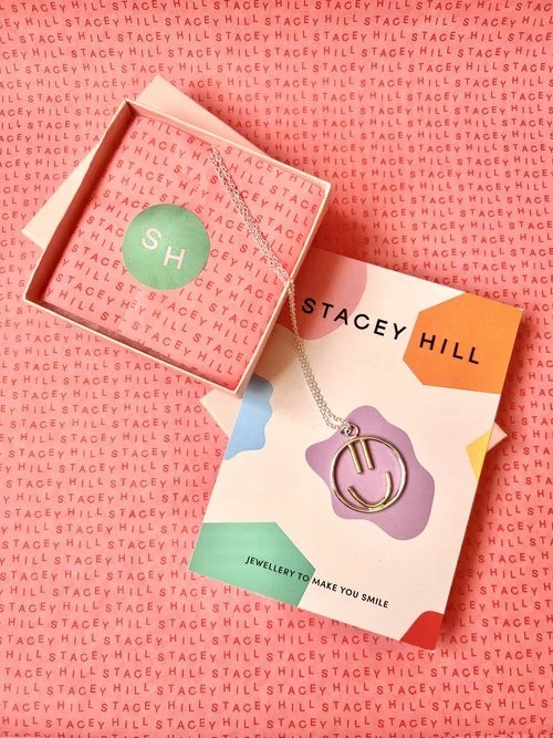 Playful silver smiley face necklace by Stacey Hill Jewellery, presented in vibrant branded packaging. A fun, modern piece handcrafted in the UK - perfect for bridesmaids or joyful bridal accessories.