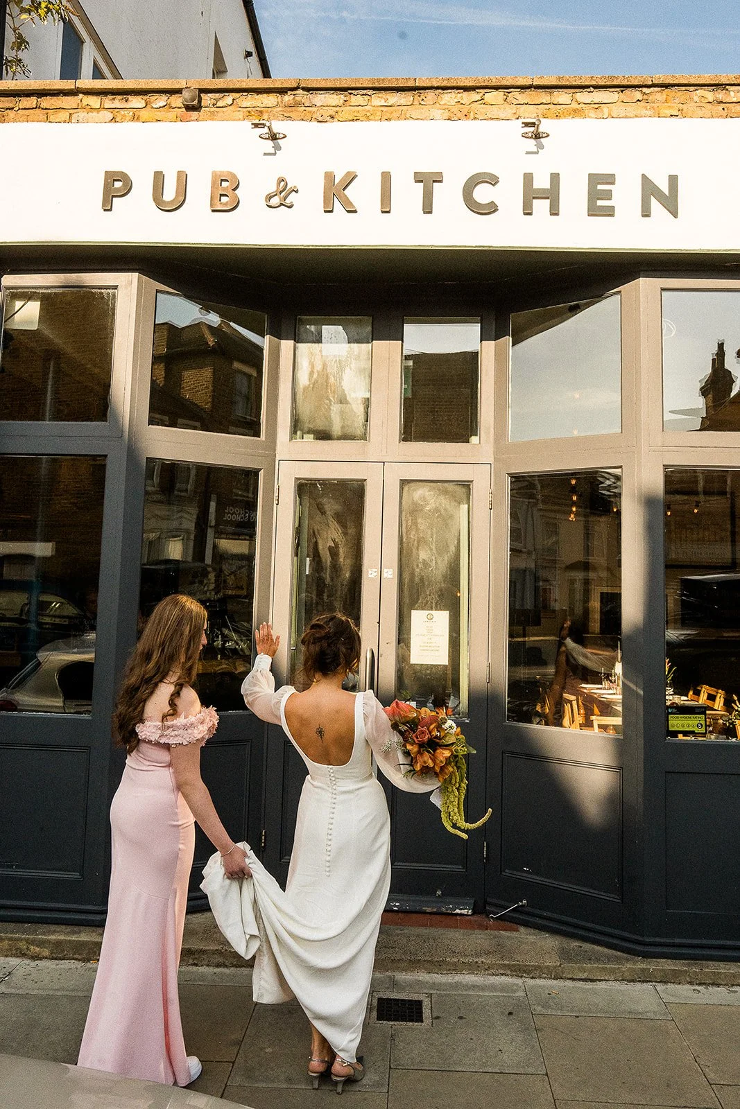 A bride walking into The Lordship pub on her wedding day.