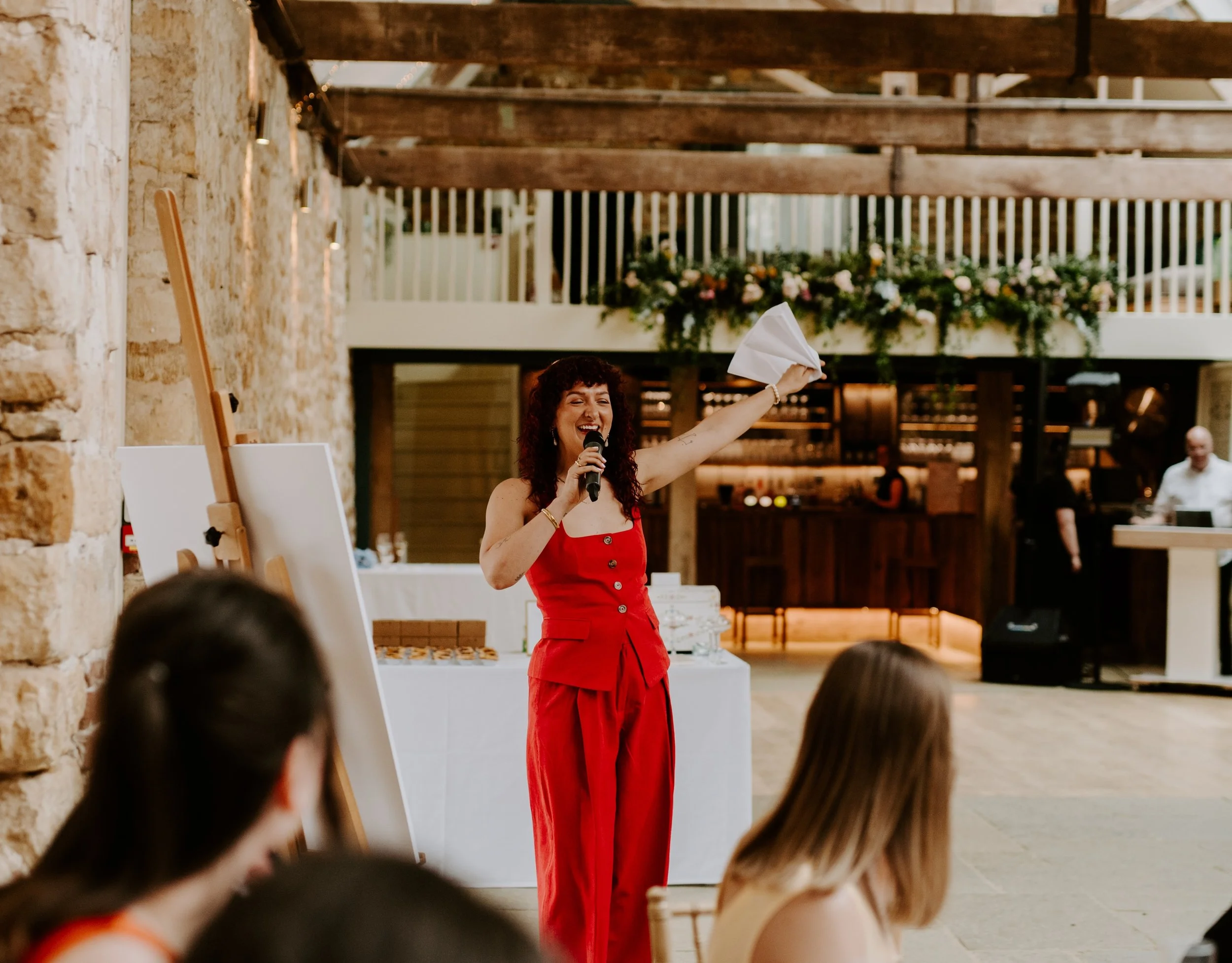 Robyn Smith Wedding Celebrant addressing a congregation, one arm aloft, smiling, and holding a microphone.