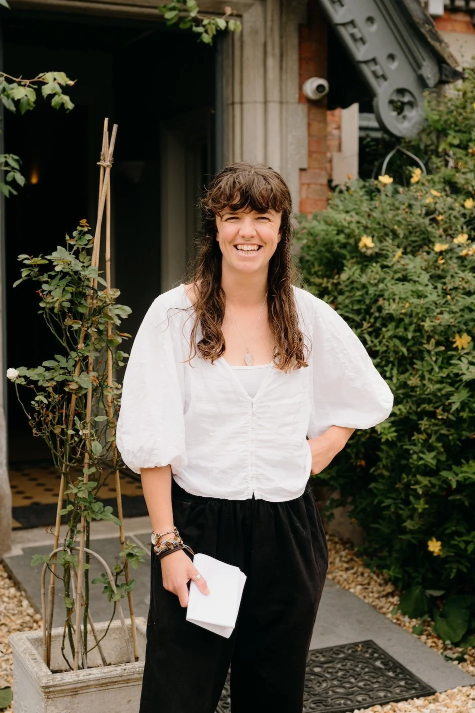 An eco wedding planner stands ready with notes in hand, capturing the calm, friendly presence behind a thoughtfully planned, sustainable wedding by Wild Soul Weddings, eco wedding planners in the UK. Pip & Clo Photography.