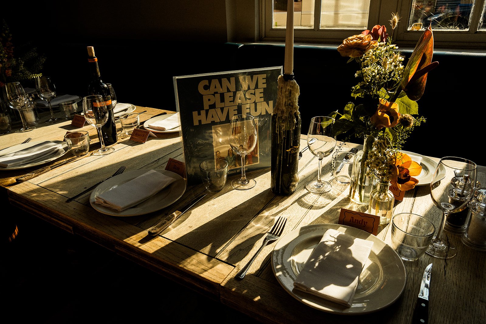 A sunkissed photo of a modern wedding table set up with flowers, candles, vinyls, and DIY stationery.