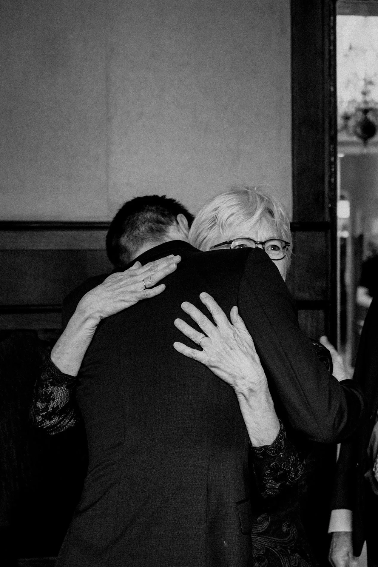 An emotional wedding moment as a guest shares a heartfelt hug, captured in timeless black and white by Quiet Mornings Wedding Photography in Scotland.