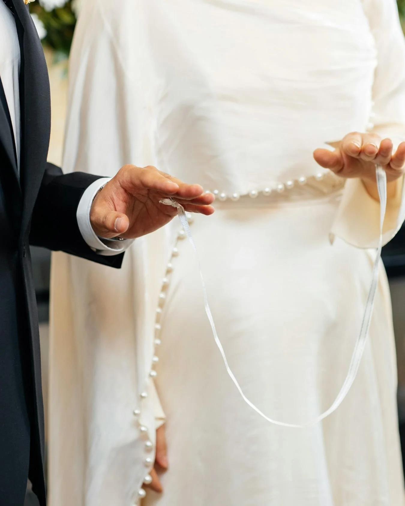 A bride and groom in the midst of a celebrant led hand fasting ceremony on their wedding day. 