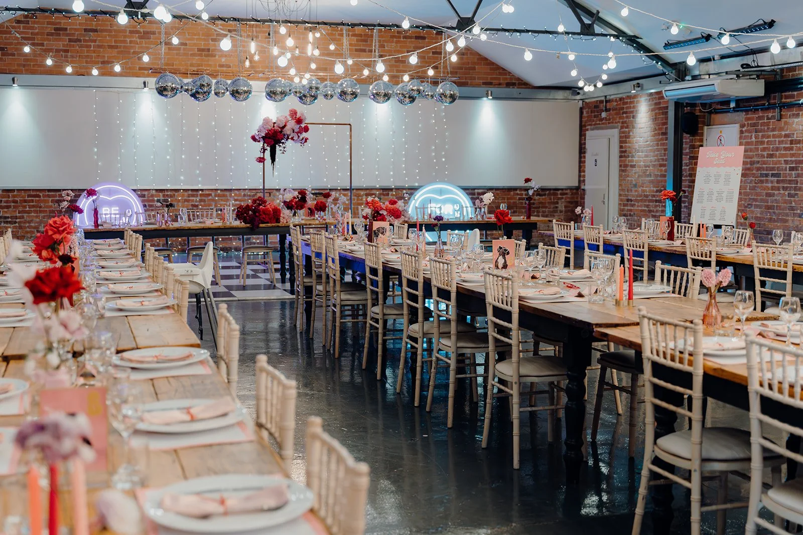 A wedding set up inside New Craven Hall in Leeds. There are neon signs and a disco ball installation.