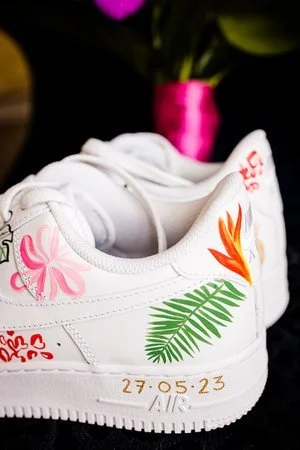 Custom hand-painted wedding trainers by Bee Davies Illustration. Featuring tropical floral designs and the couple’s wedding date in gold, these personalised shoes blend comfort and creativity - perfect for modern brides wanting unique, wearable artwo
