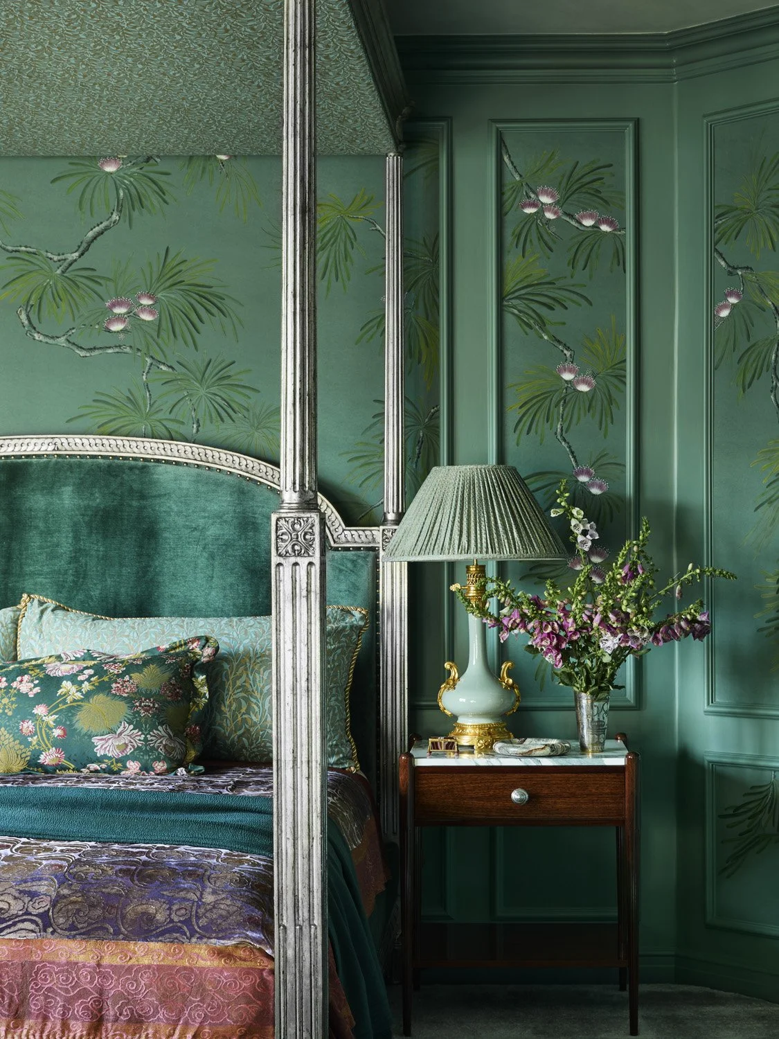 Jewel-toned green and teal bedroom with rich fabrics and paneled wallpaper.