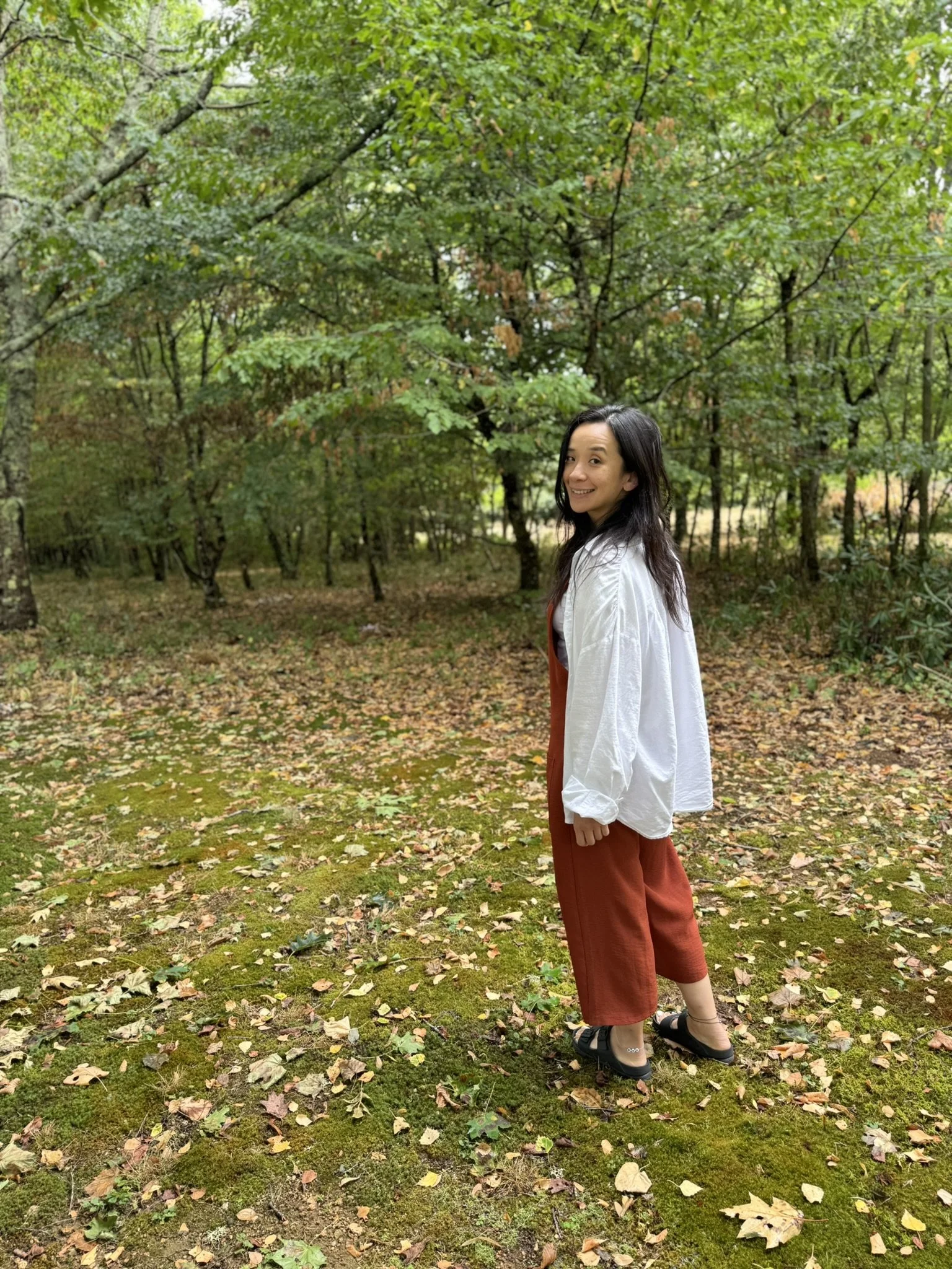 Hypnotherapist Li Lamb in Ilkley, Yorkshire smiling in a natural woodland setting, symbolising clarity, transformation, and emotional balance.