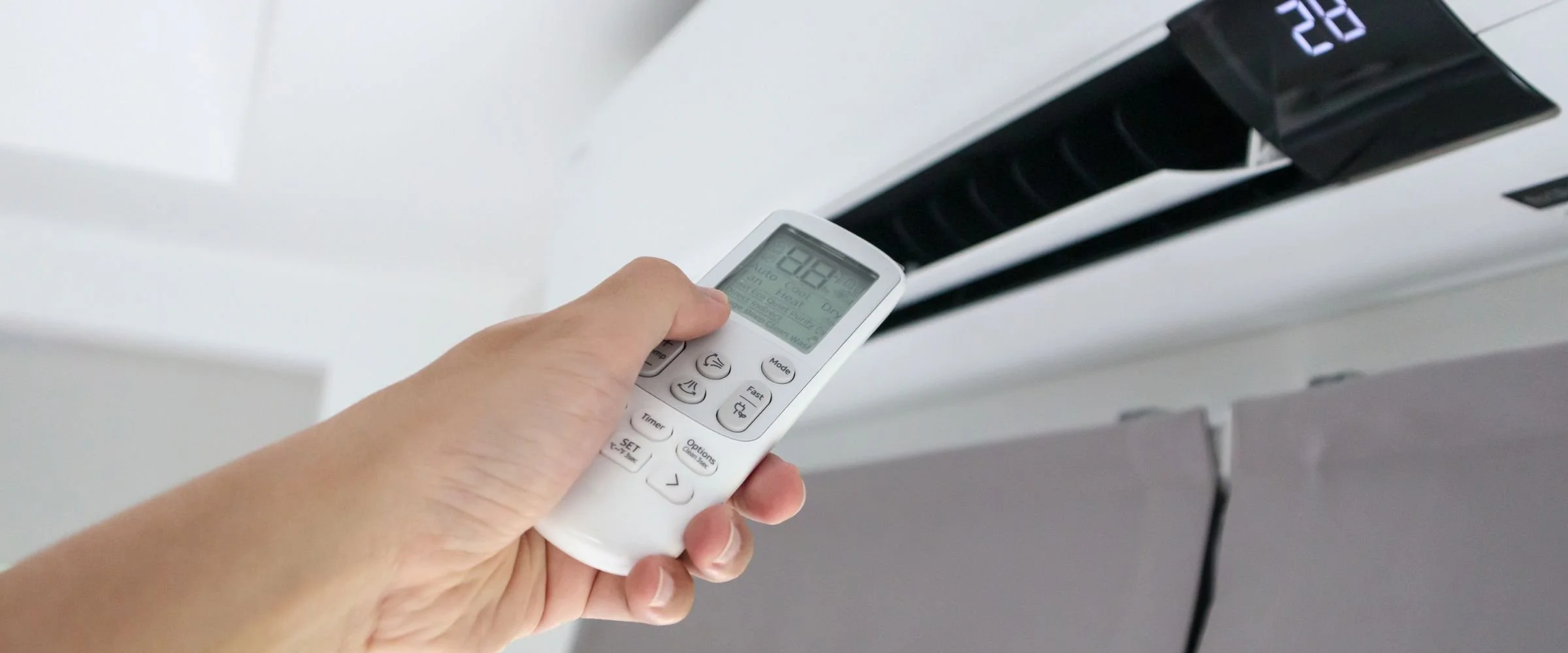 Person adjusting the thermostat on an air conditioning unit with a remote control