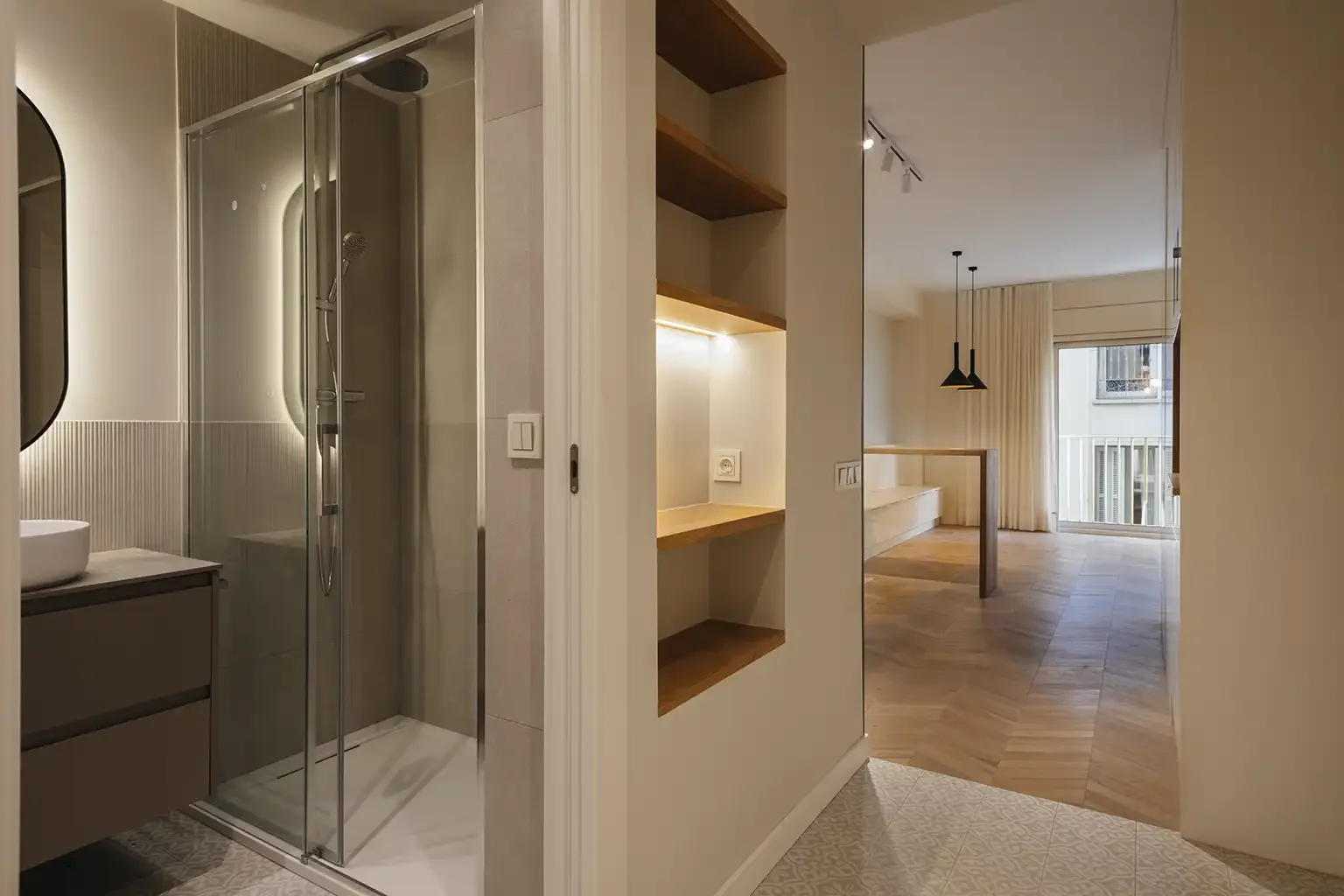Interior de un piso reformado en Barcelona con entrada, baño y zona de estar de concepto abierto.
