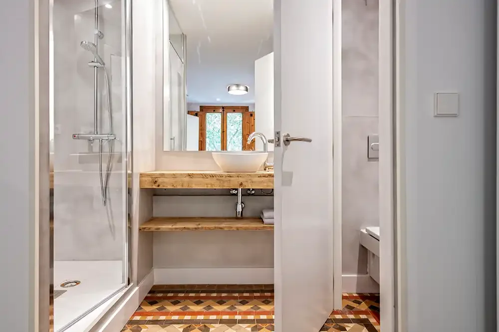 Barselona'da kiralık bir daire için modern duş alanı ve ahşap lavabo ünitesiyle yenilenmiş banyo.
