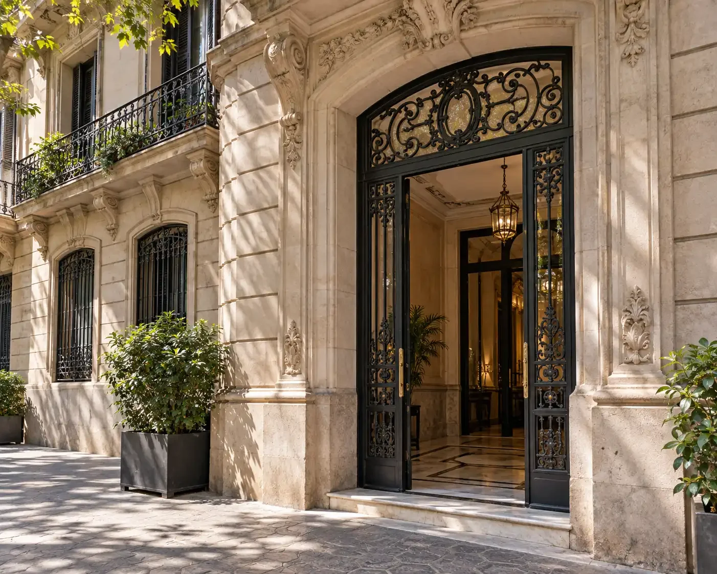Entrada de piedra iluminada por el sol y puerta de hierro de un edificio residencial en Barcelona.