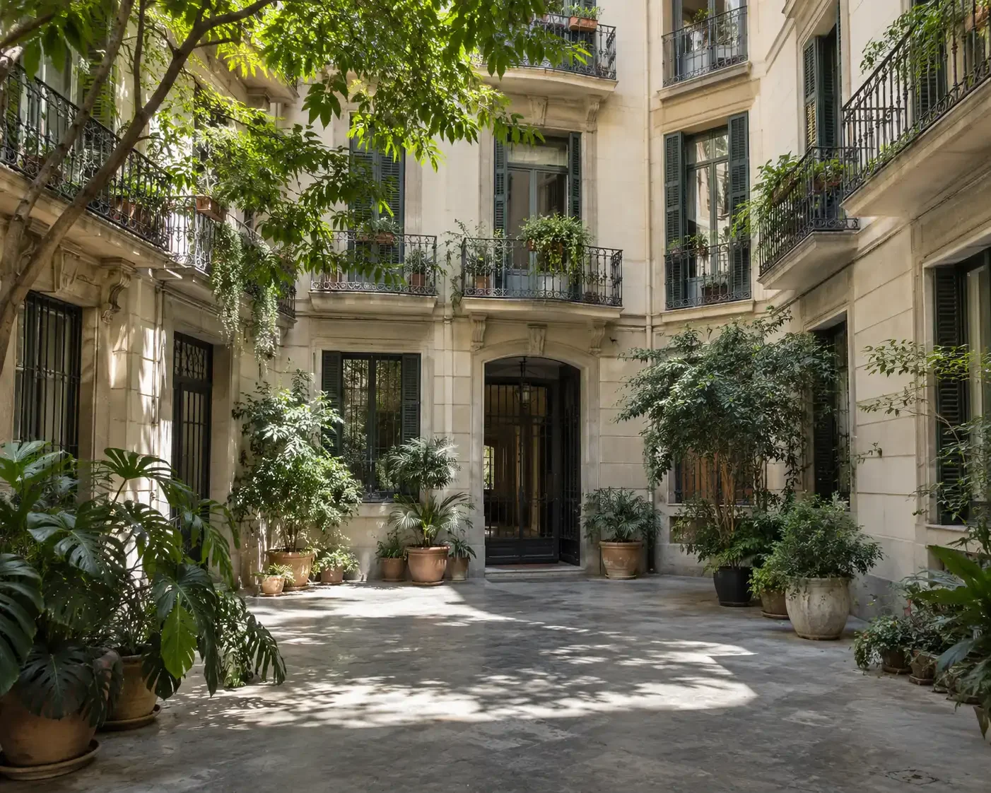Patio ajardinado de un edificio residencial de Barcelona con balcones de hierro forjado