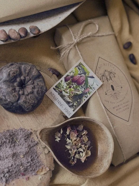 Dried herbs and natural products on a wooden surface, with a wrapped package tied with twine and a colorful plant tag.