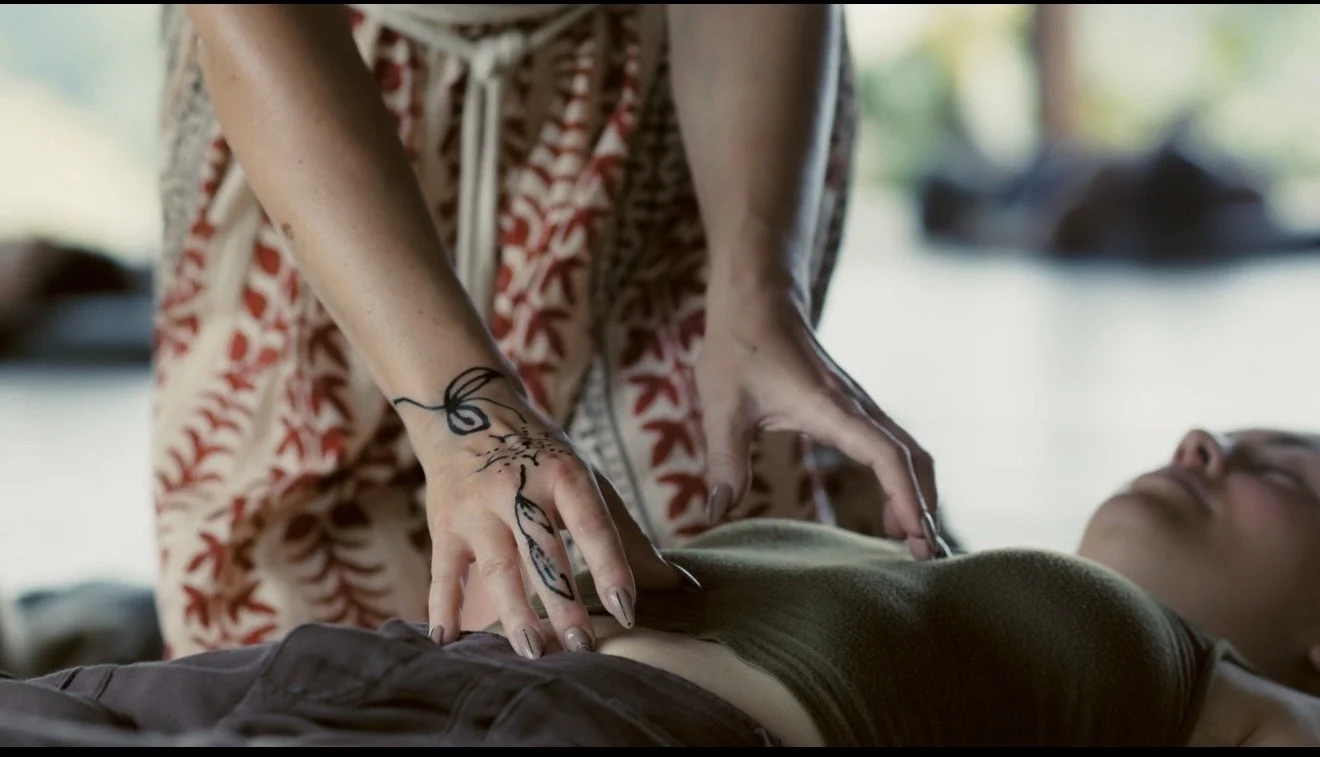 Person performing CPR on a woman lying on a surface outdoors