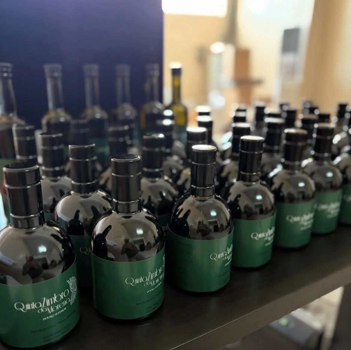 Várias garrafas de azeite virgem-extra com rótulo verde na mesa.