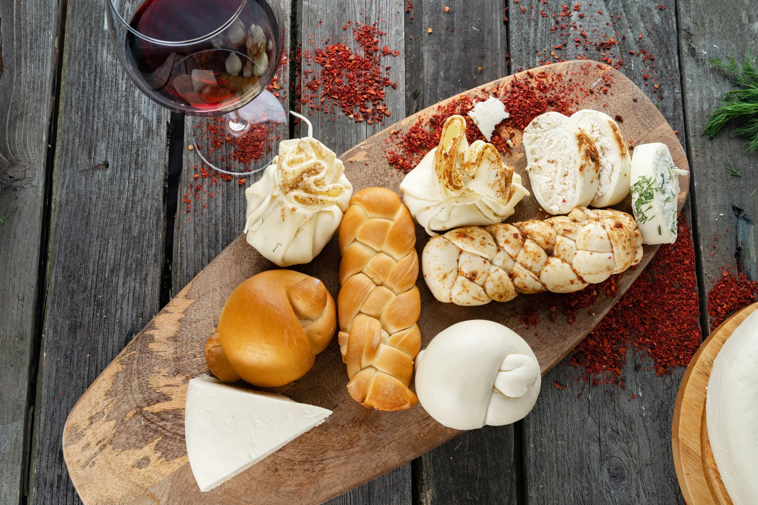 Inside a wine cellar or cave, with large clay wine amphoras arranged along a narrow stone path and a barrel with a pump in the background.