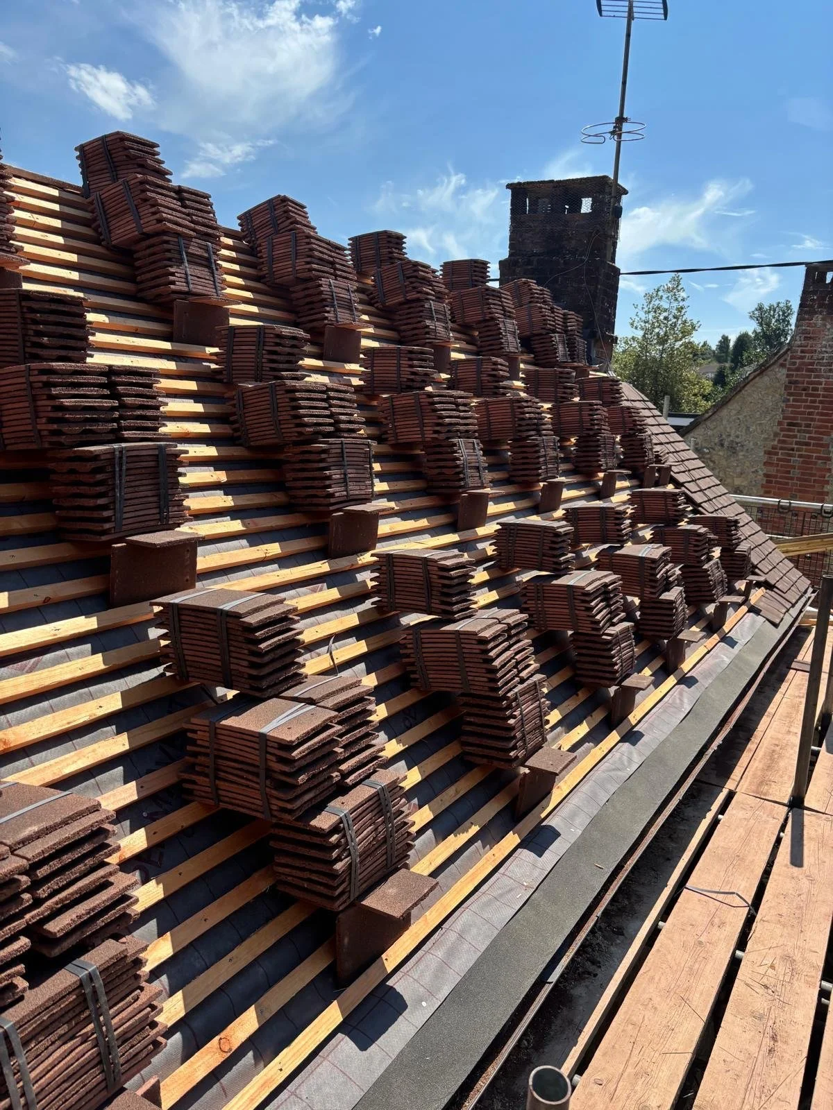 Roof being replaced with new tiles stacked in bundles on the roof surface.