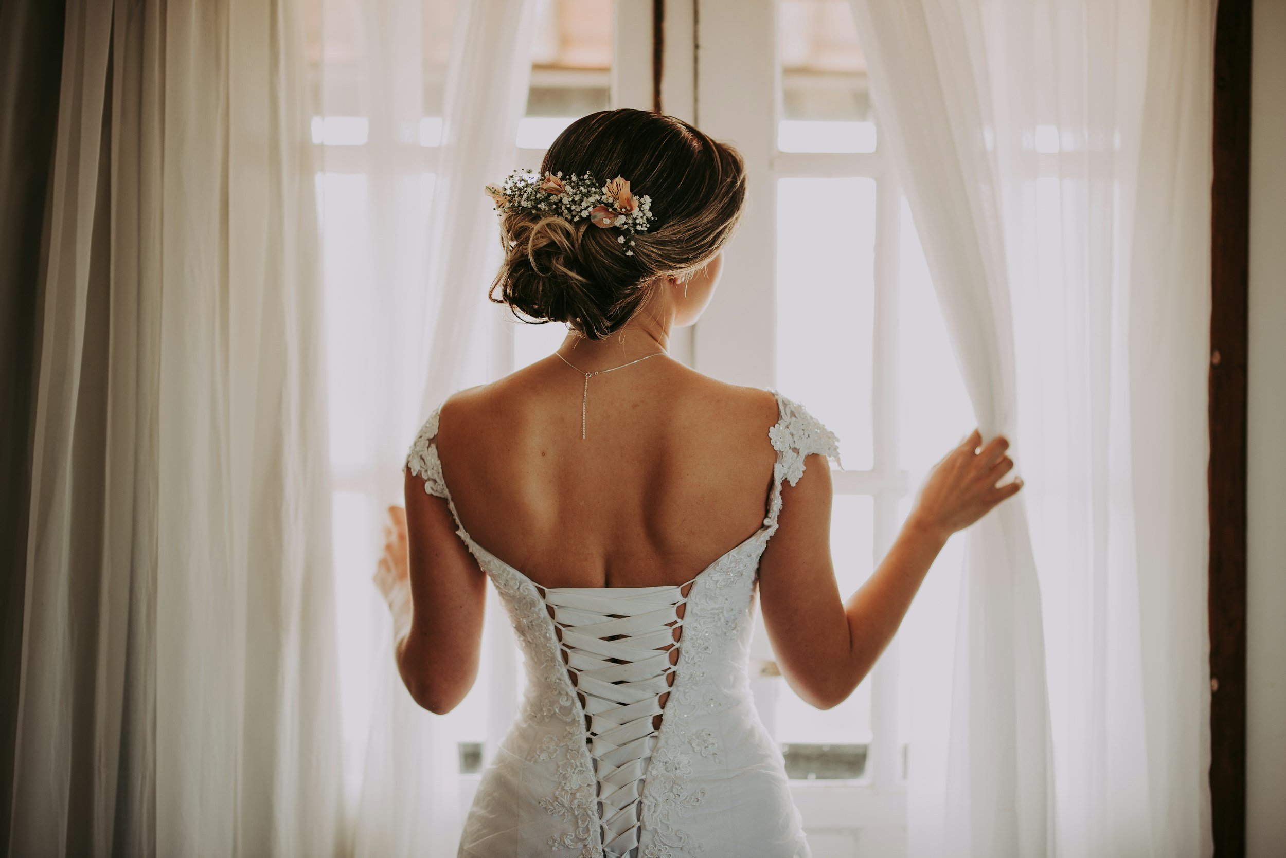 A bride smiling as she carries her designer wedding dress out of Dress Me Up Lincoln, ready to take home the same day.