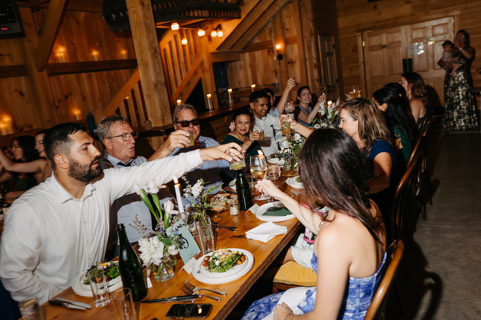 Guests enjoying dinner in the barn at Tops'l farm during a wedding reception photography