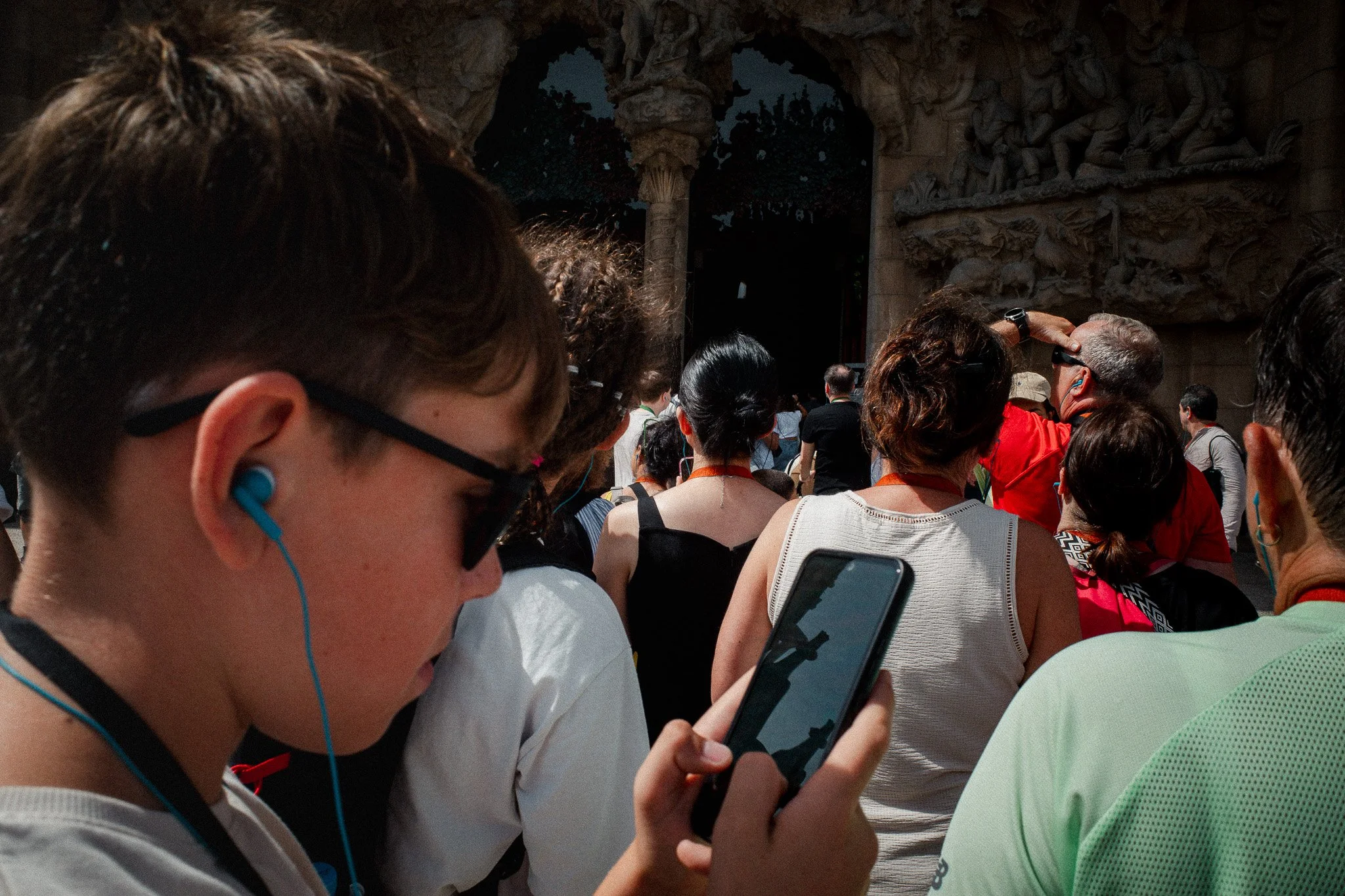 Un chico con auriculares mira el móvil entre la multitud que rodea el templo
