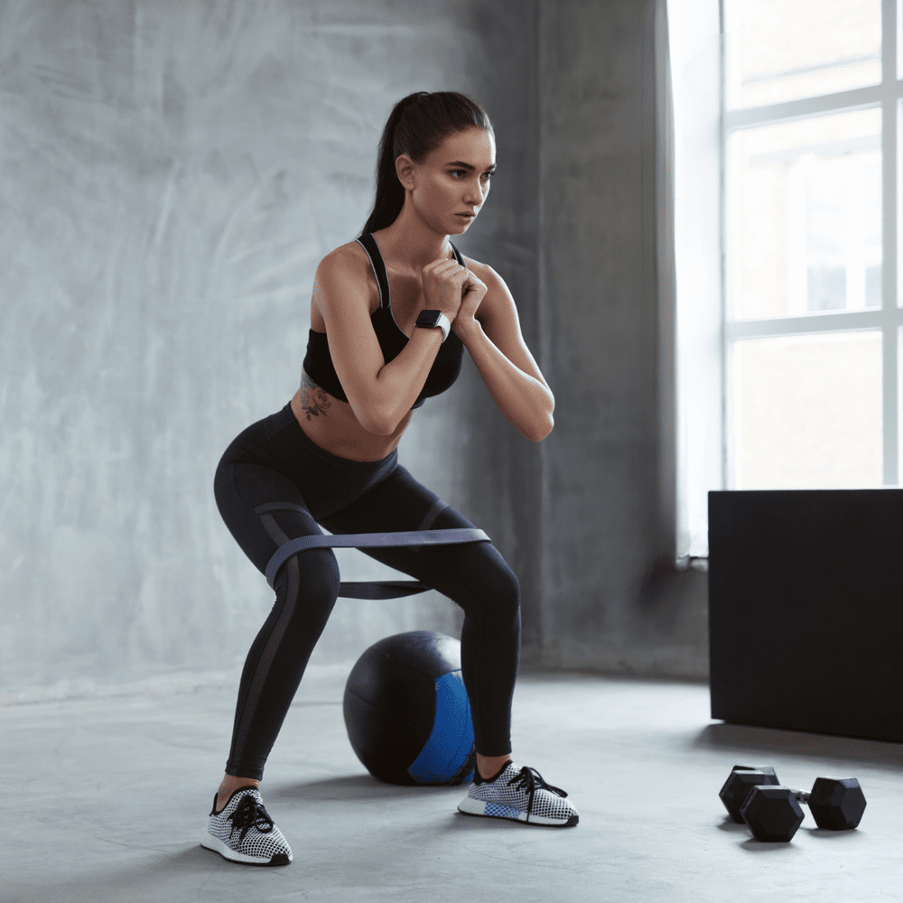 A woman doing a banded squat in a gym