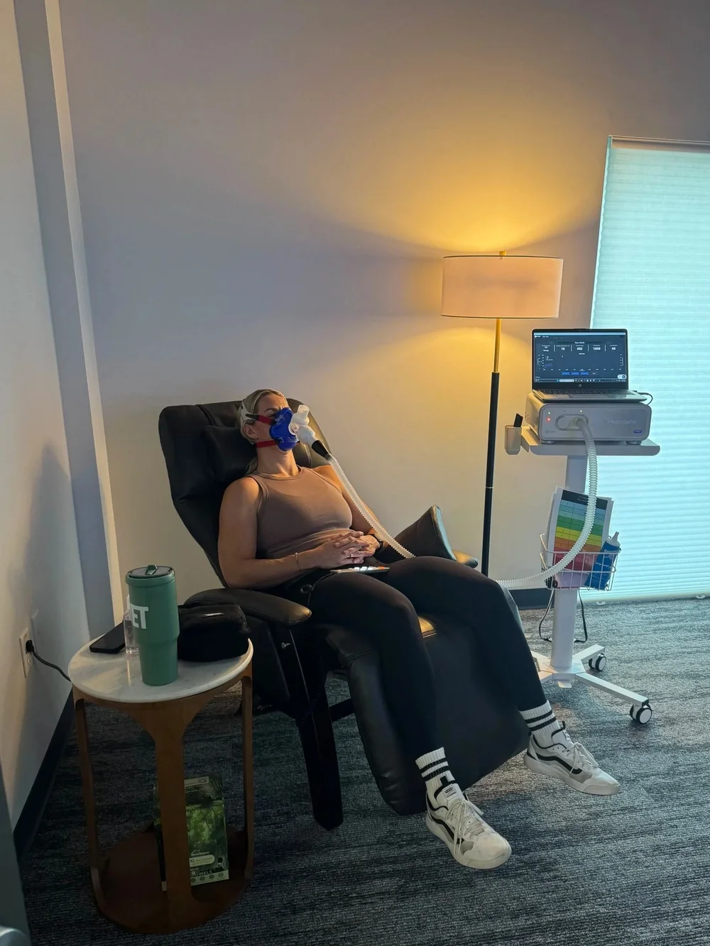 A client resting in a recliner with a breath mask during an RMR test at DexaFit Tampa