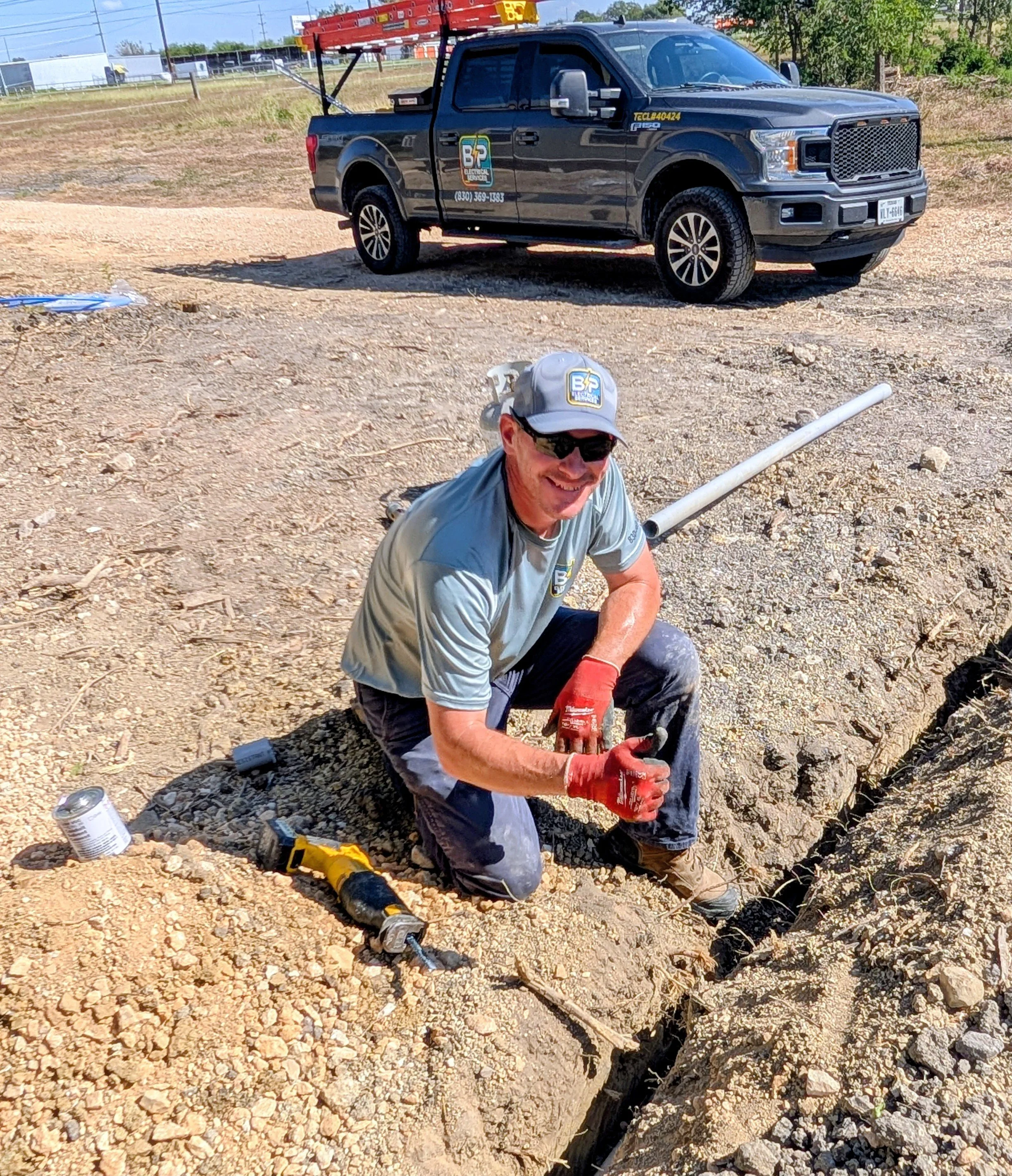 Jason Payne, owner of BP Electrical Services, poses next to a trench for electrical wiring on a job site.