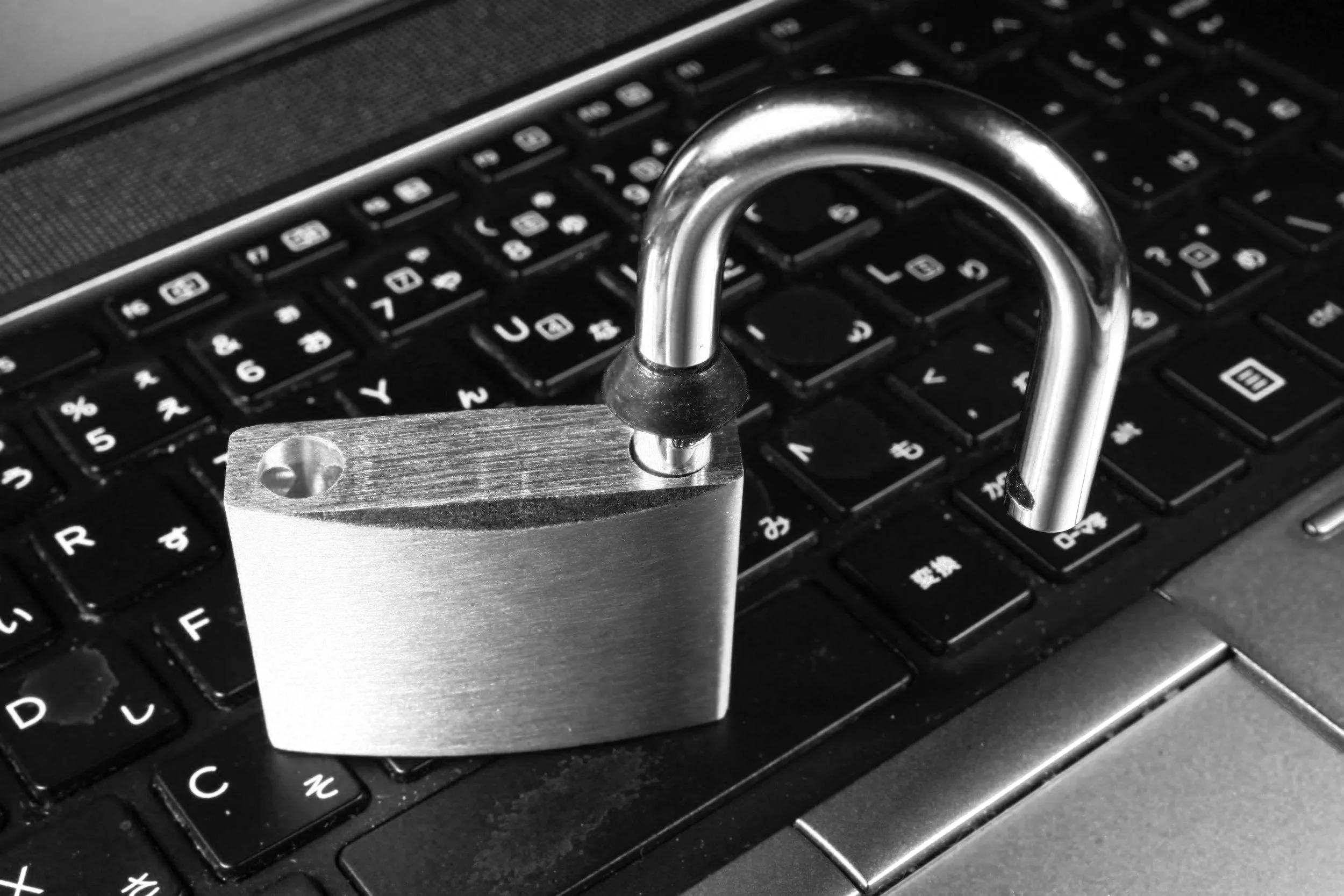 A laptop keyboard with a metal chain and a large gold padlock on top, illuminated by red and green lights.