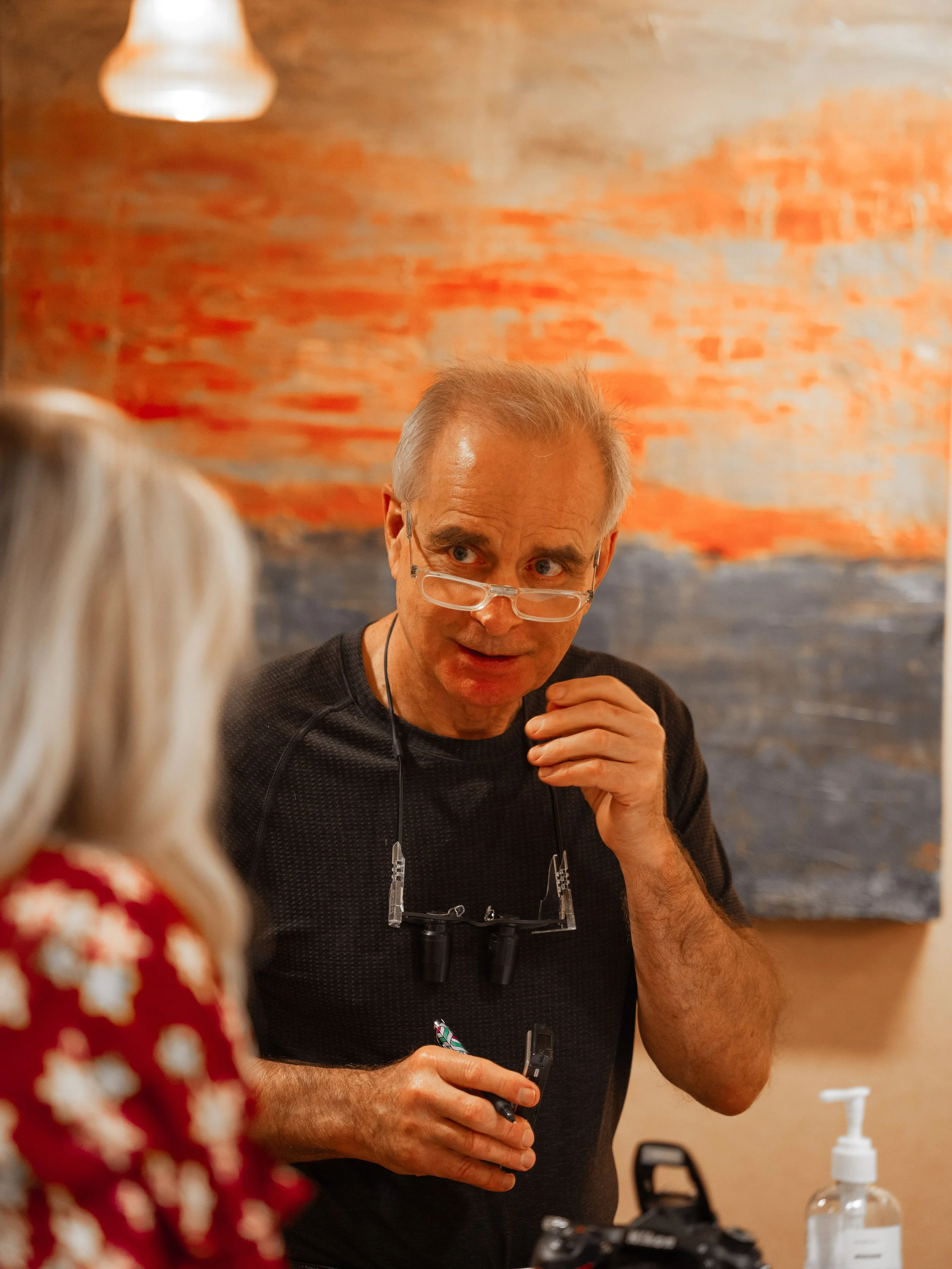 Dr. Chariker with glasses and a black shirt is speaking to a woman. Dr. Chariker explaining or answering questions, possibly in an interview or conversation.