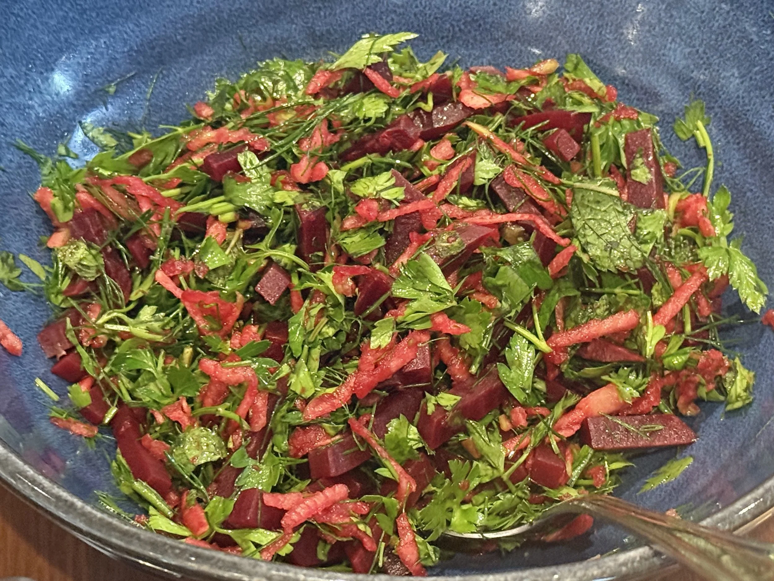 Fresh chopped tabbouleh salad with herbs, beetroot, and shredded apples in a bowl.