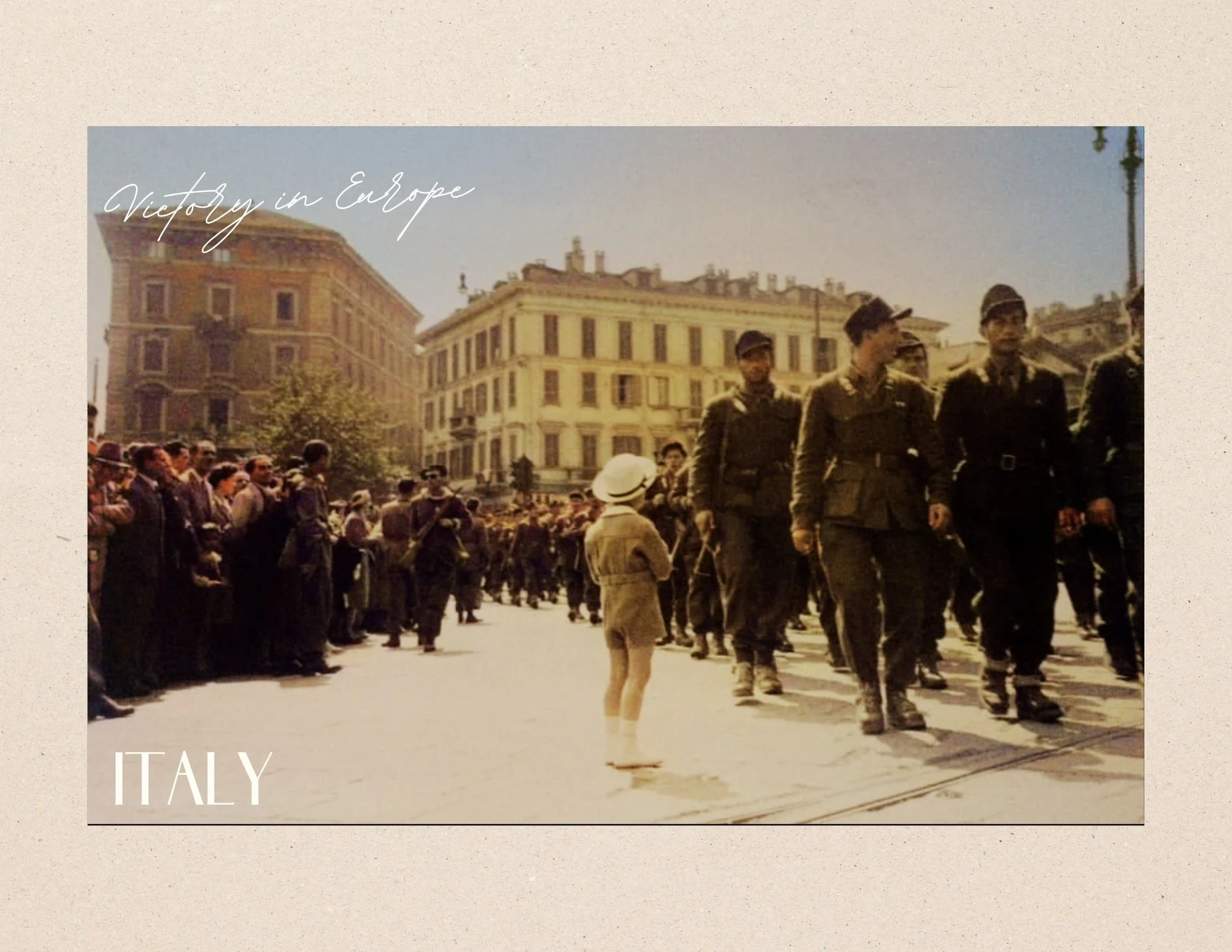 Vintage photo of soldiers marching in a parade in Italy, with a crowd of onlookers on the side of the street, and historic buildings in the background.