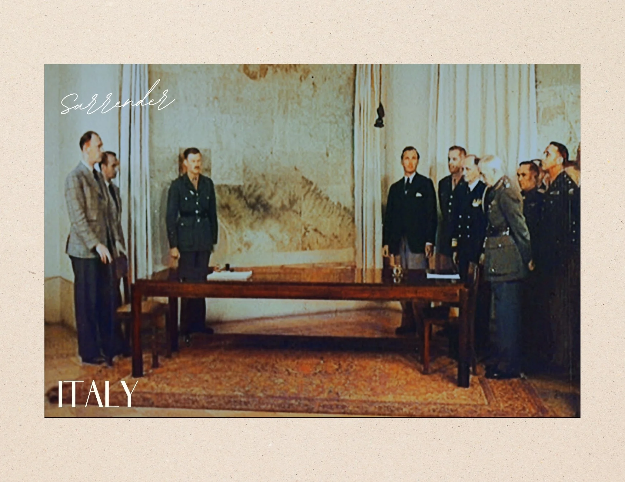 A photograph of a formal meeting with military officers and civilians in a room with a large painting or mural on the back wall. There is a table in the center, and people are standing on either side, facing each other.