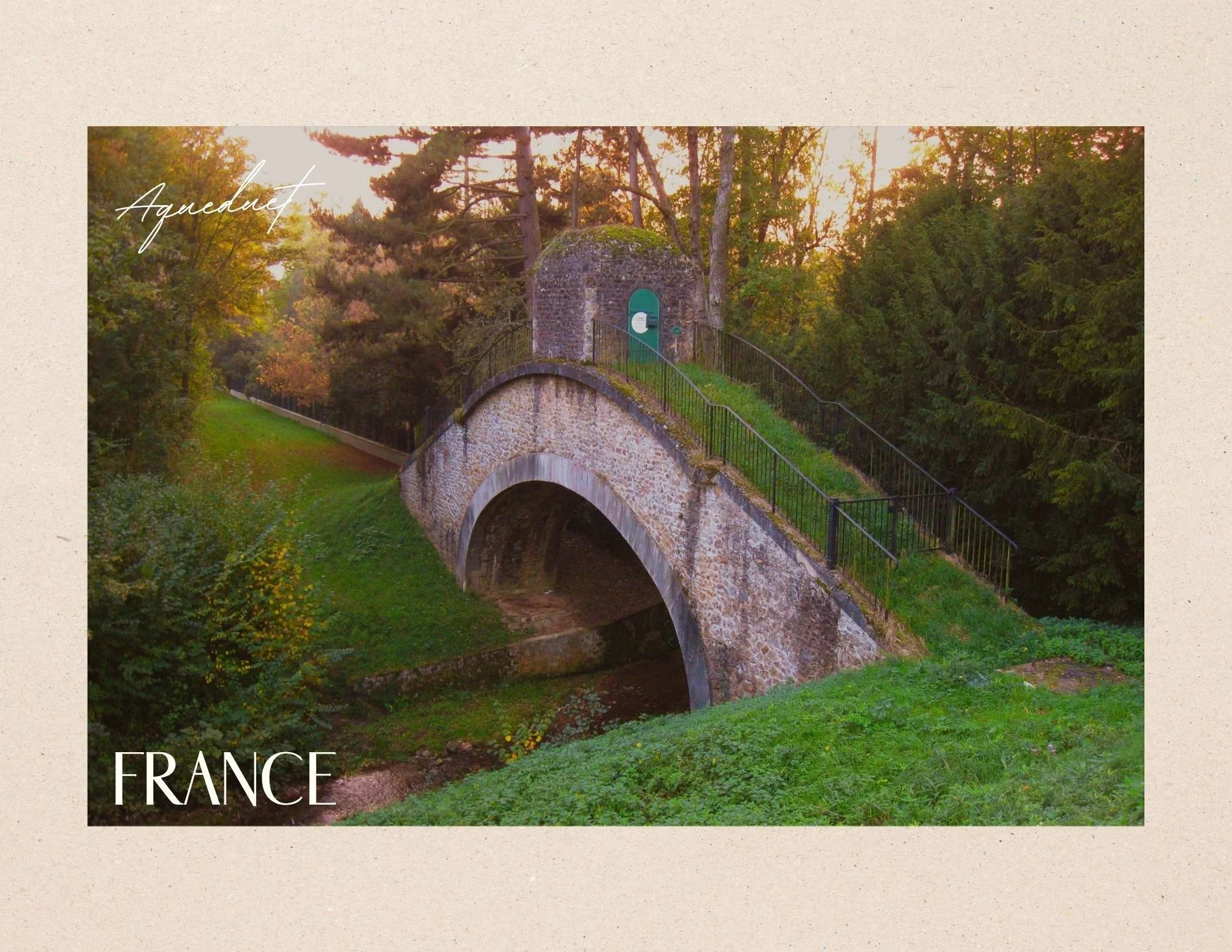 A stone bridge over a small stream surrounded by greenery, with a small structure on top of the bridge, and trees in the background during sunset in France. An Aqueduct.