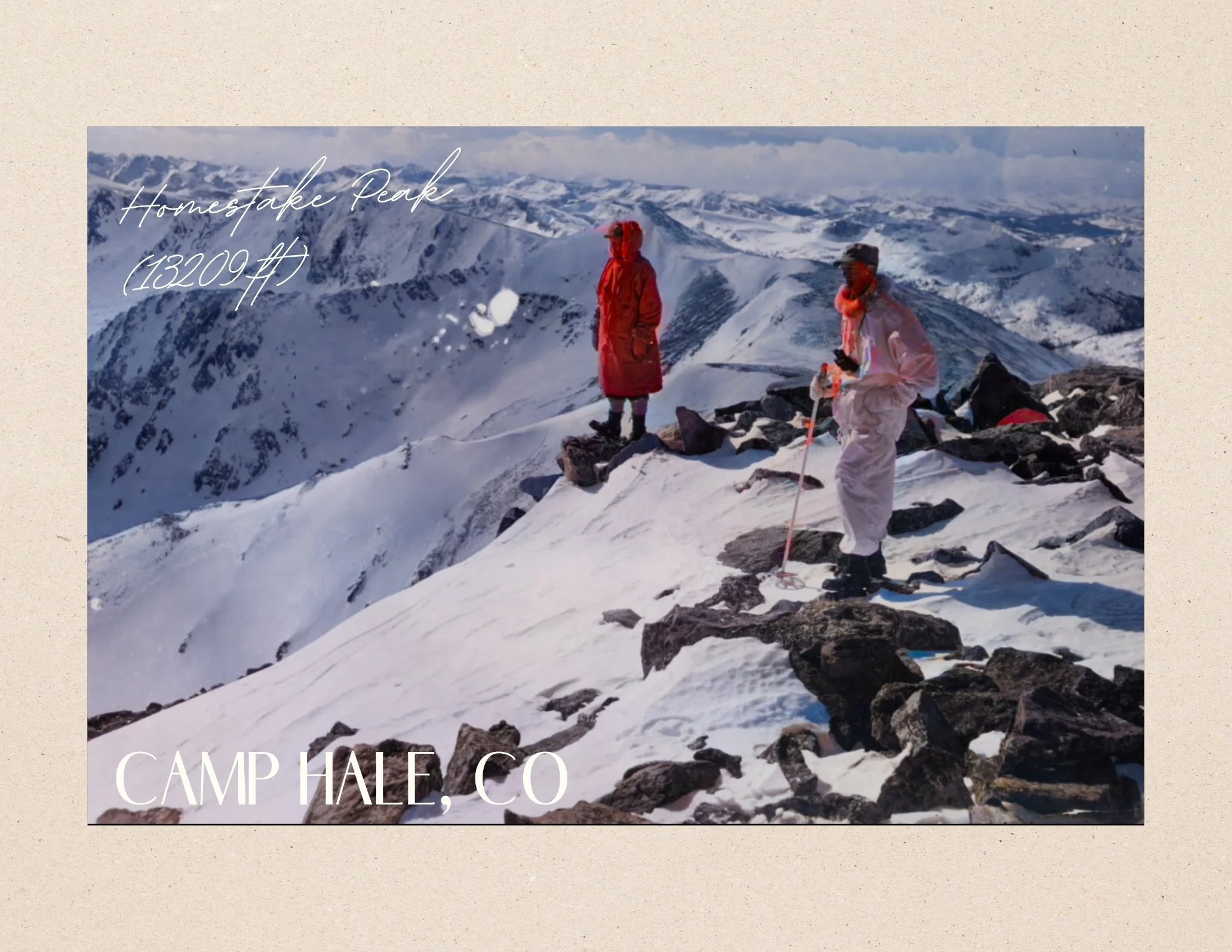 Snow-covered mountain landscape with two people dressed in winter gear standing among rocks, overlooking the mountains at Homestake Peak in Colorado.