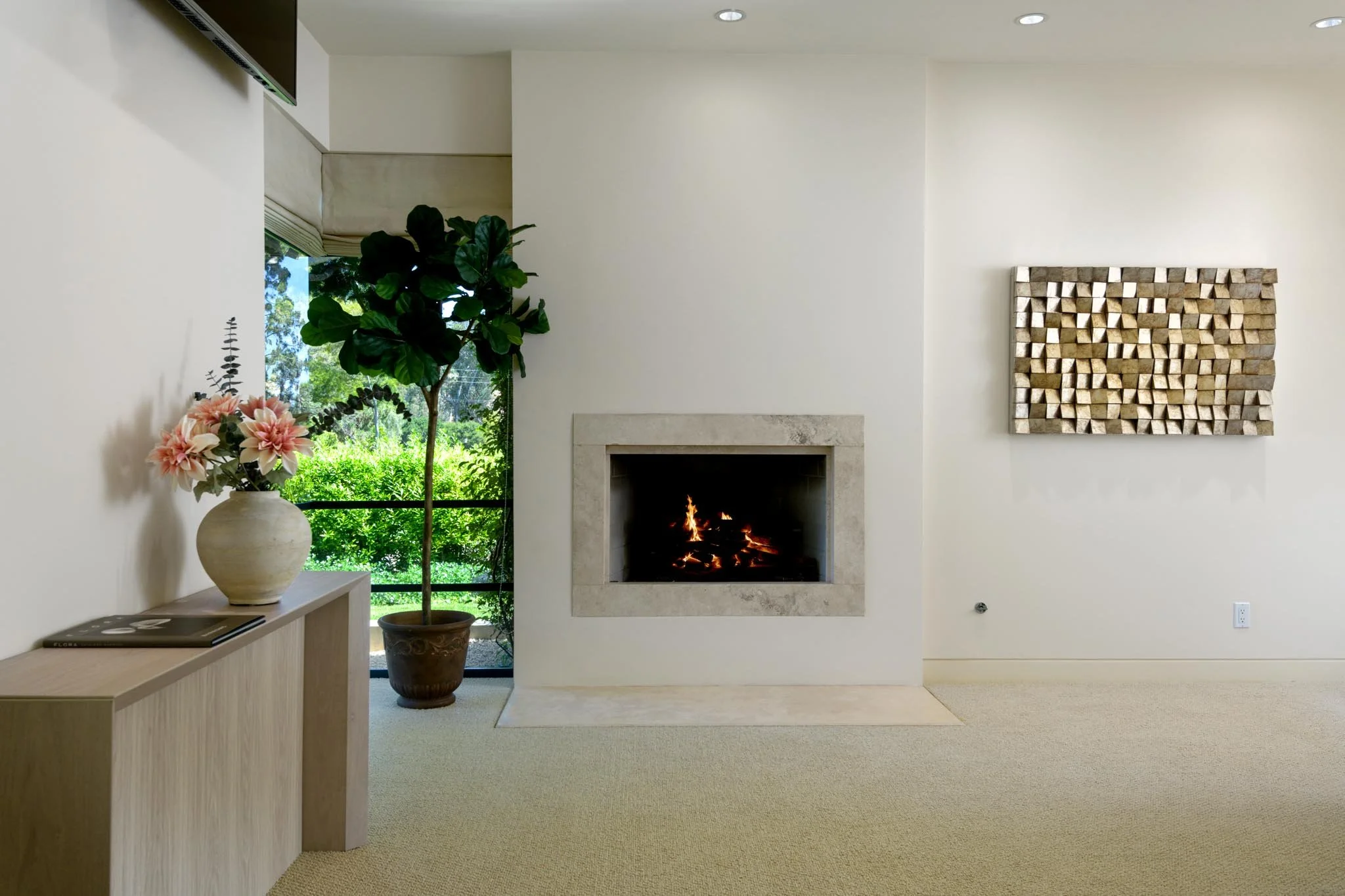 Living room with a fireplace, potted plant, floral arrangement, and wall art