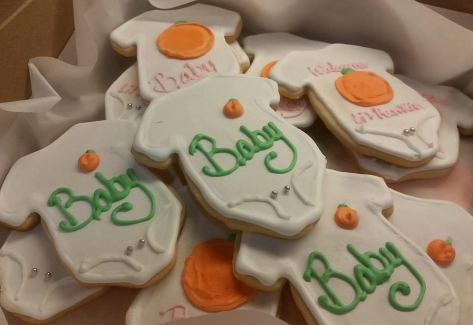 Orange, white and green baby shower sugar cookies shaped like a onsie