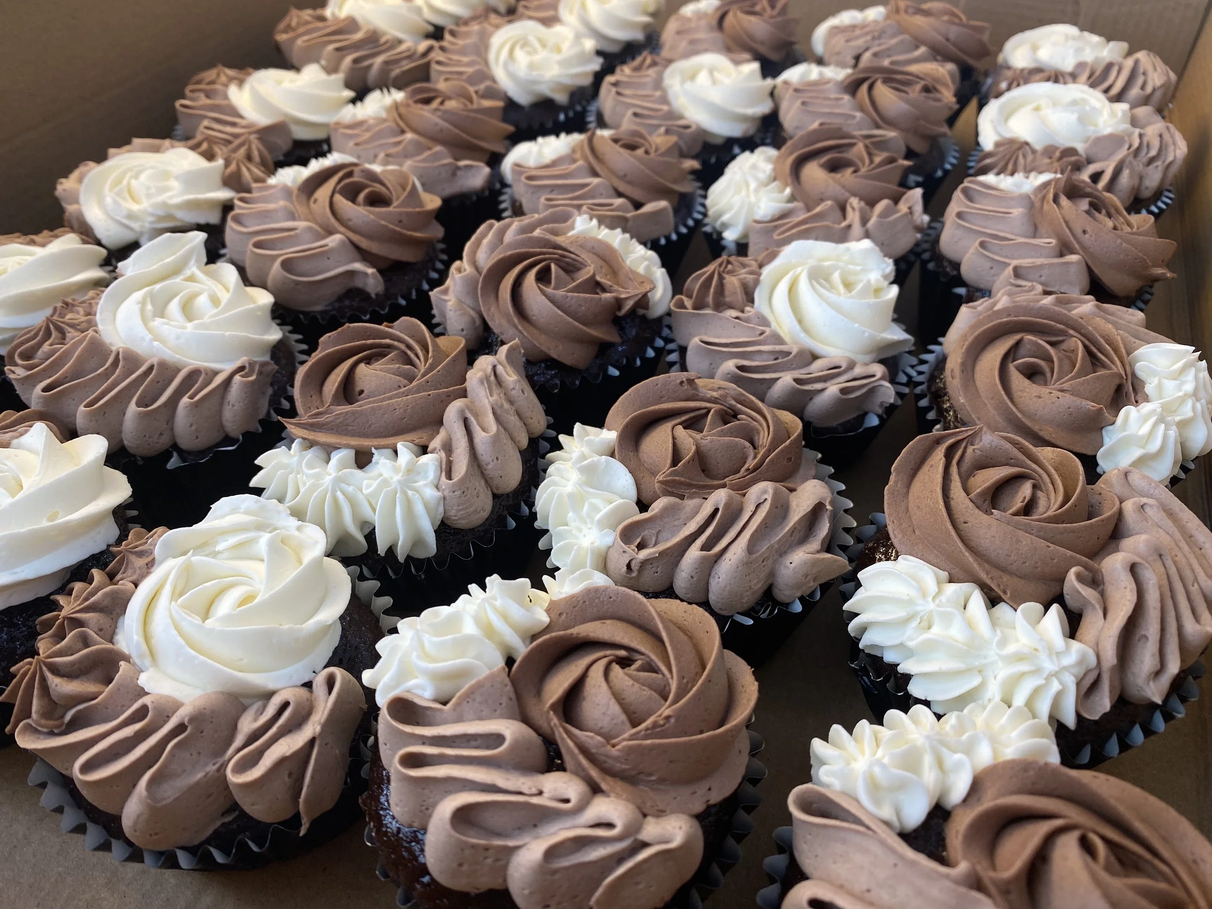 Assorted cupcakes topped with swirls of vanilla and chocolate frosting.
