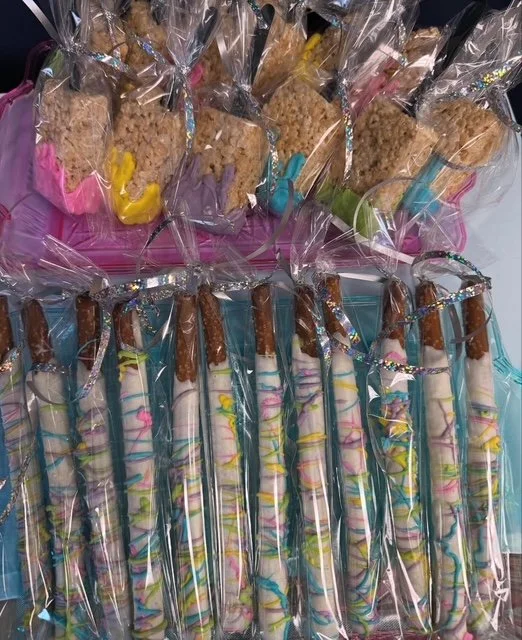 Assorted decorated cookies wrapped in clear plastic, some with colorful icing and sprinkles, arranged on a table.
