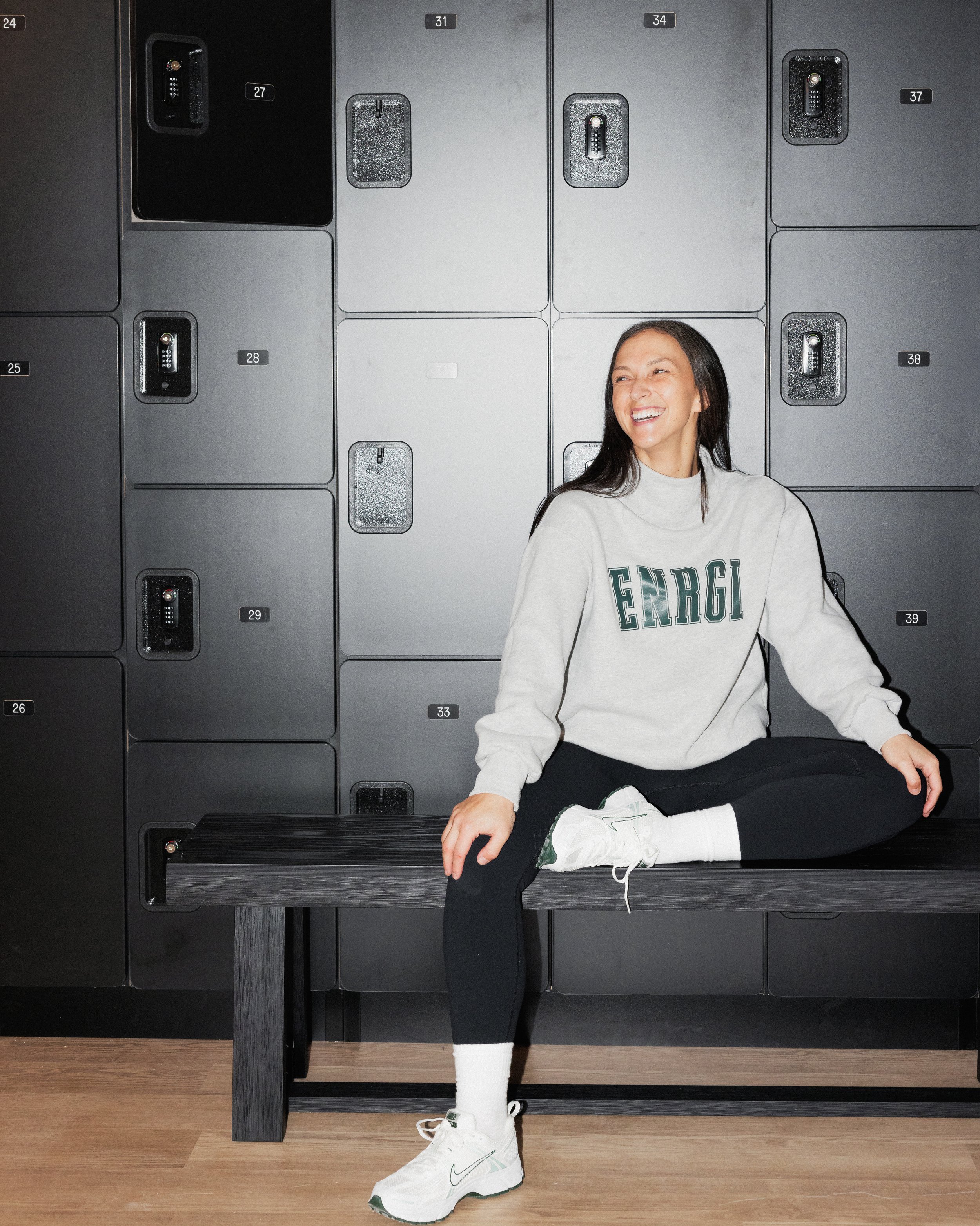 Brandi Schmiedicker, founder of ENRGI Fitness, sitting in the studio at ENRGI, a boutique indoor cycling, strength, and sculpt fitness studio in Williamsville, NY.