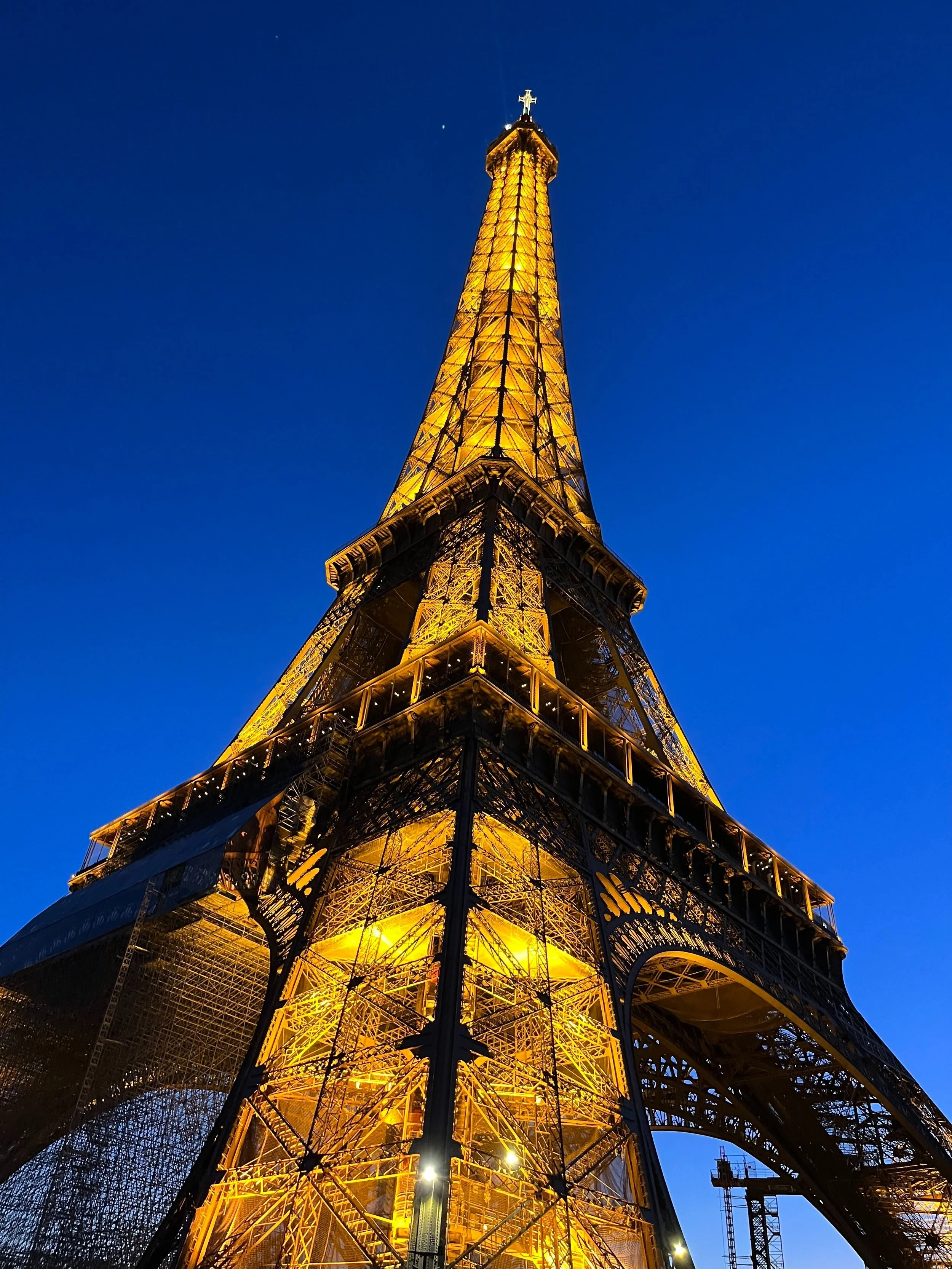 The Eiffel Tower illuminated with golden lights against a dark blue evening sky.