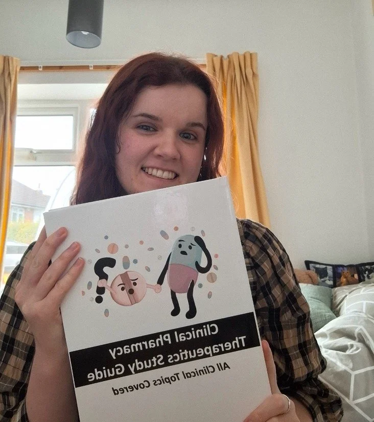 Young woman with red hair smiling and holding a sign with text about clinical pharmacy and all clinical topics covered.