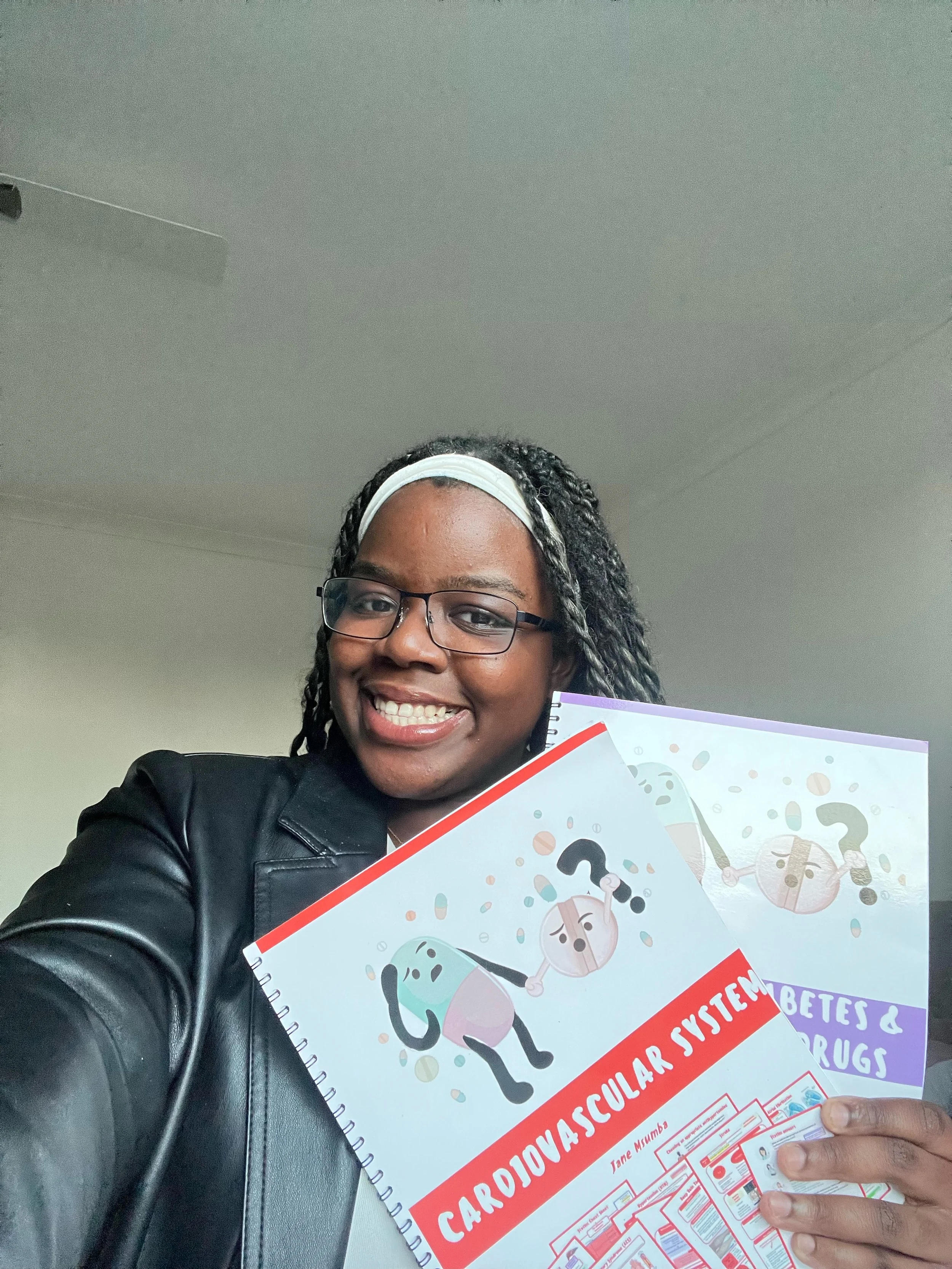 A woman smiling and holding educational booklets about the cardiovascular system and drugs.