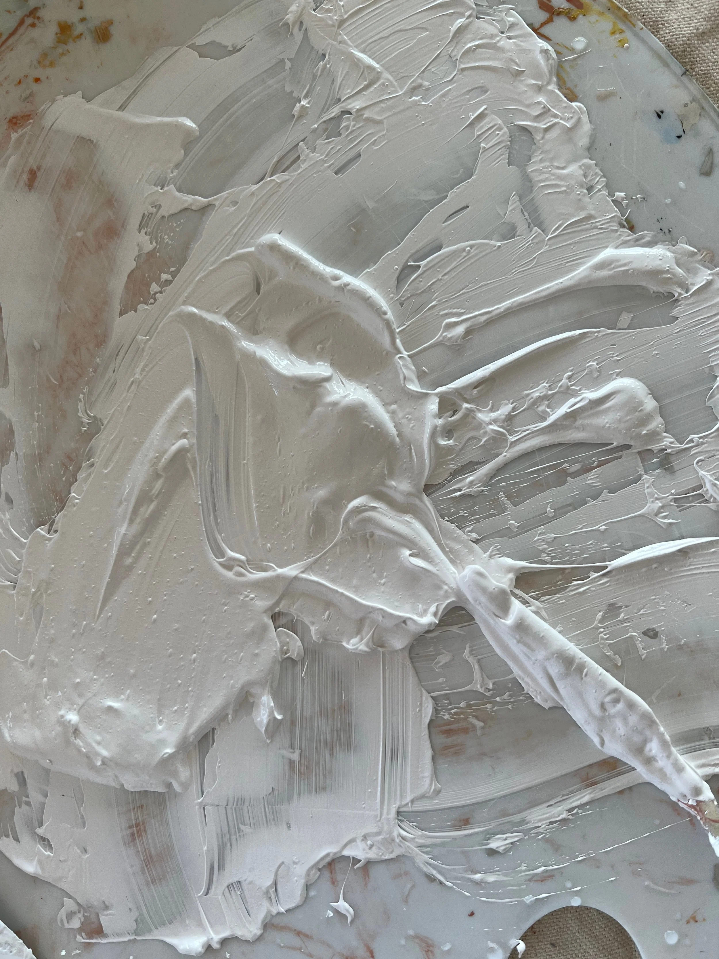 A surface with white paint or plaster smeared across it, with a paintbrush or spatula visible.