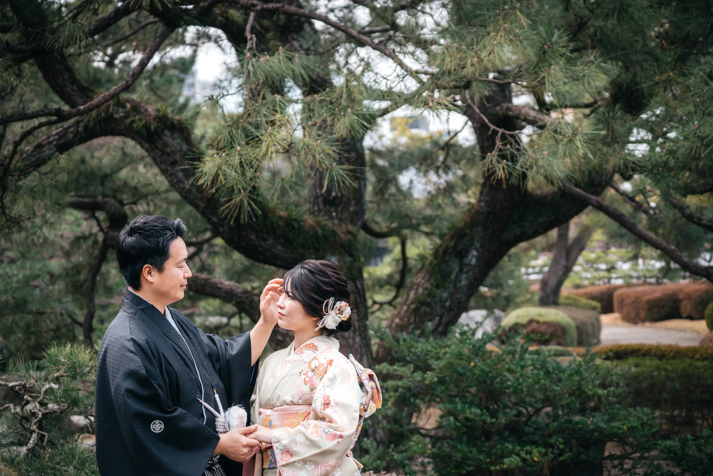 着物を着た女性と男性が木の下で祝福し合っている写真