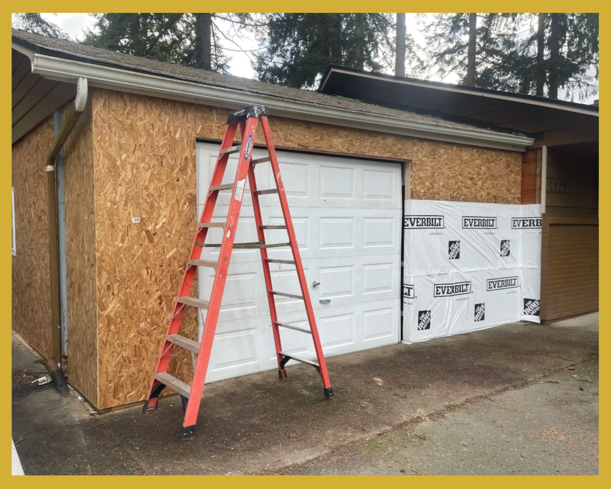 A house with a garage door in the process of being remodeled; partially covered with exterior sheathing labeled 'Everbilt' and a red ladder leaning against the wall.