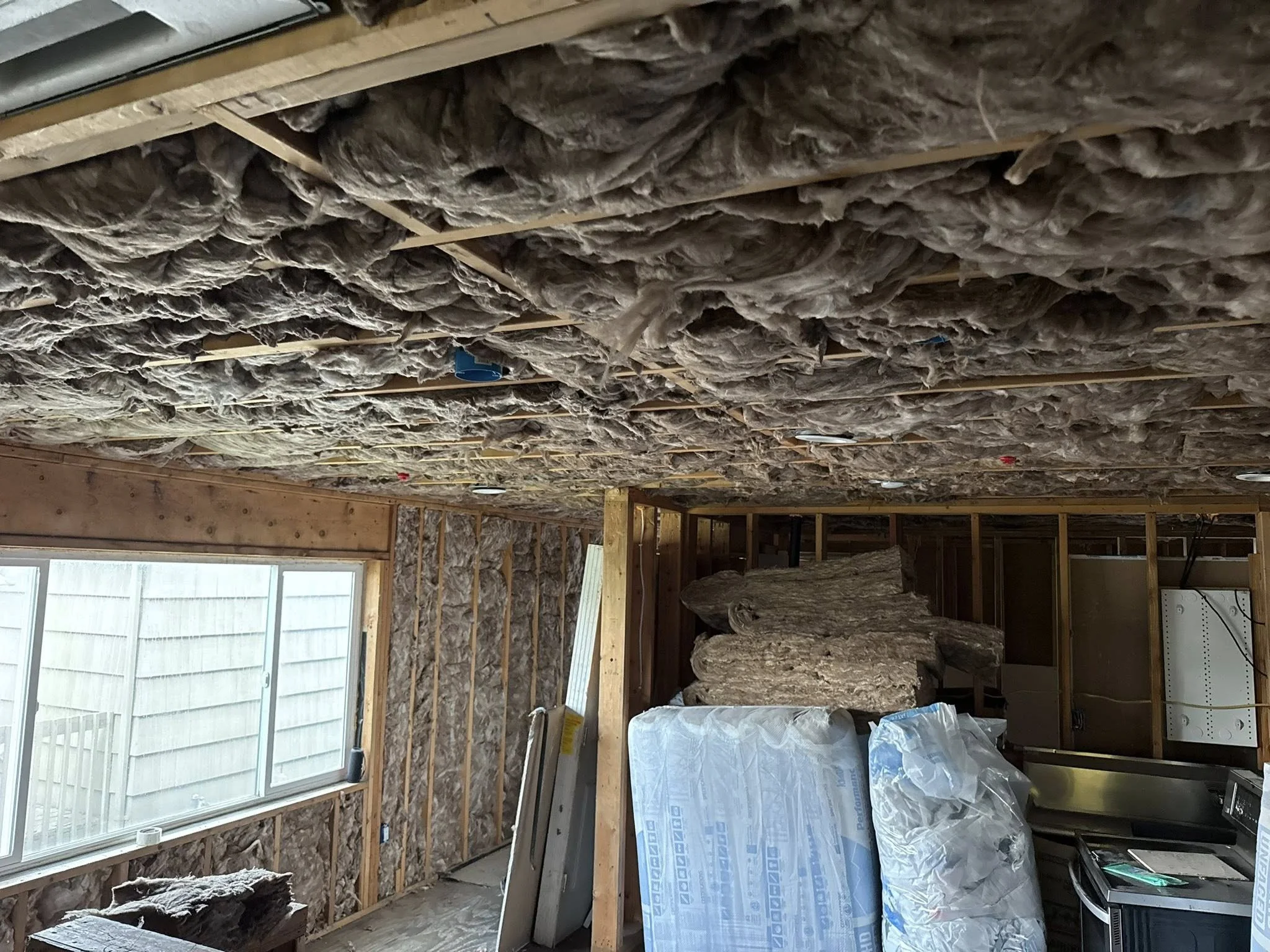 Insulated walls and ceiling of a construction site or basement with insulation material and exposed wooden framing.