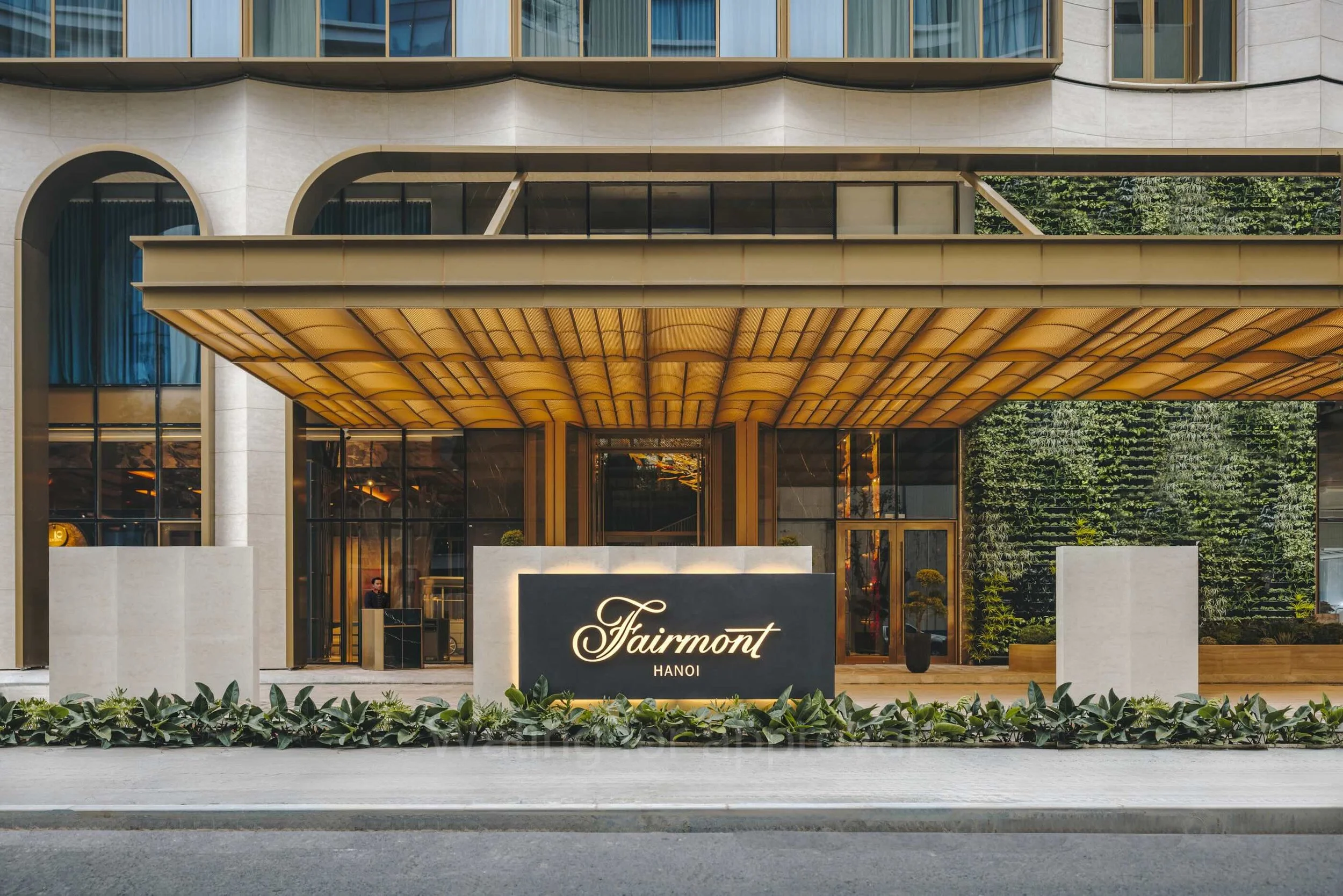 Hotel entrance with a large illuminated sign that reads 'Fairmont Hanoi', and a decorative awning above the doorway. Vietnam luxury Accor hotel with free nights. Stay 3 pay 2.