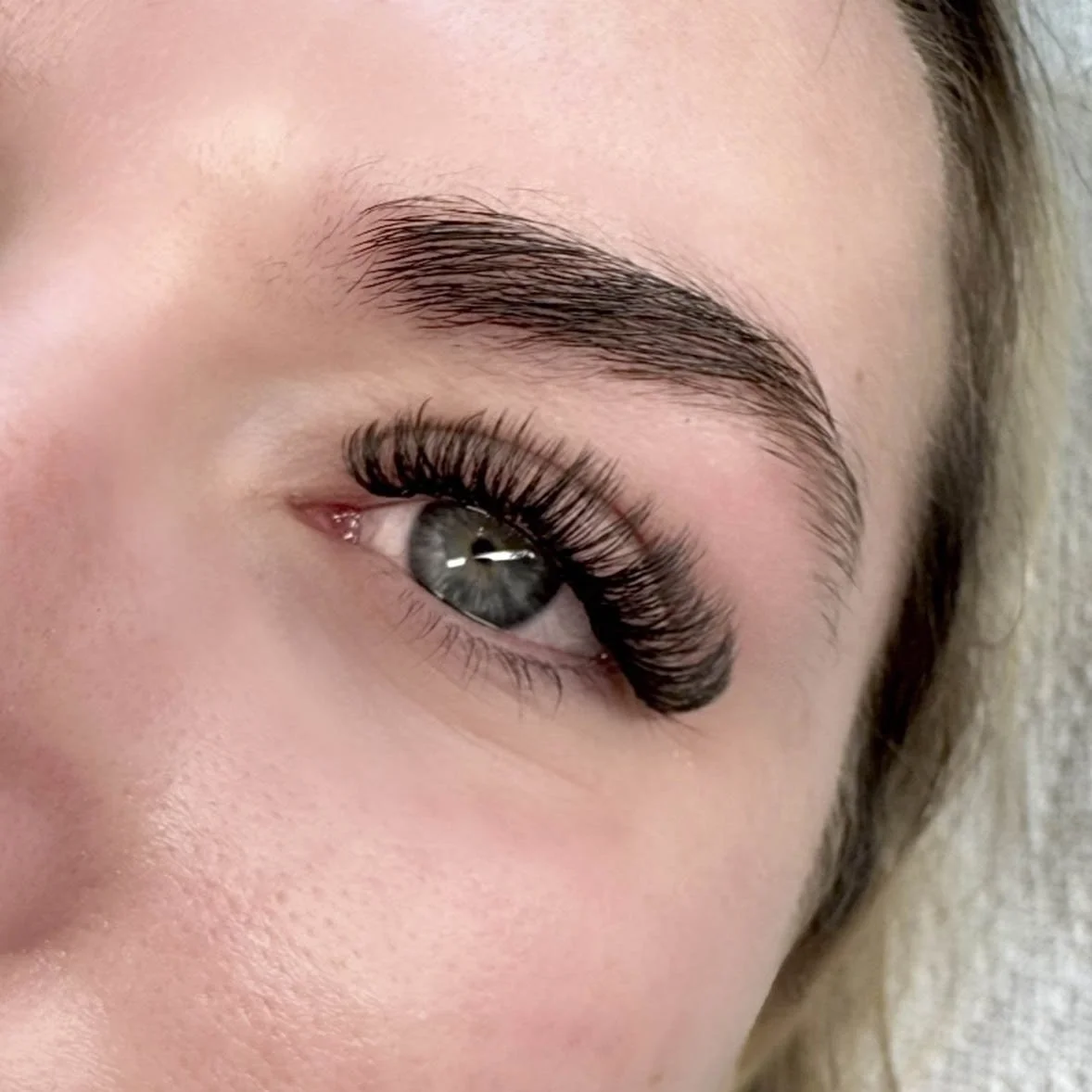 Close-up of a woman's eye showcasing her long, curled eyelashes and well-groomed eyebrow.