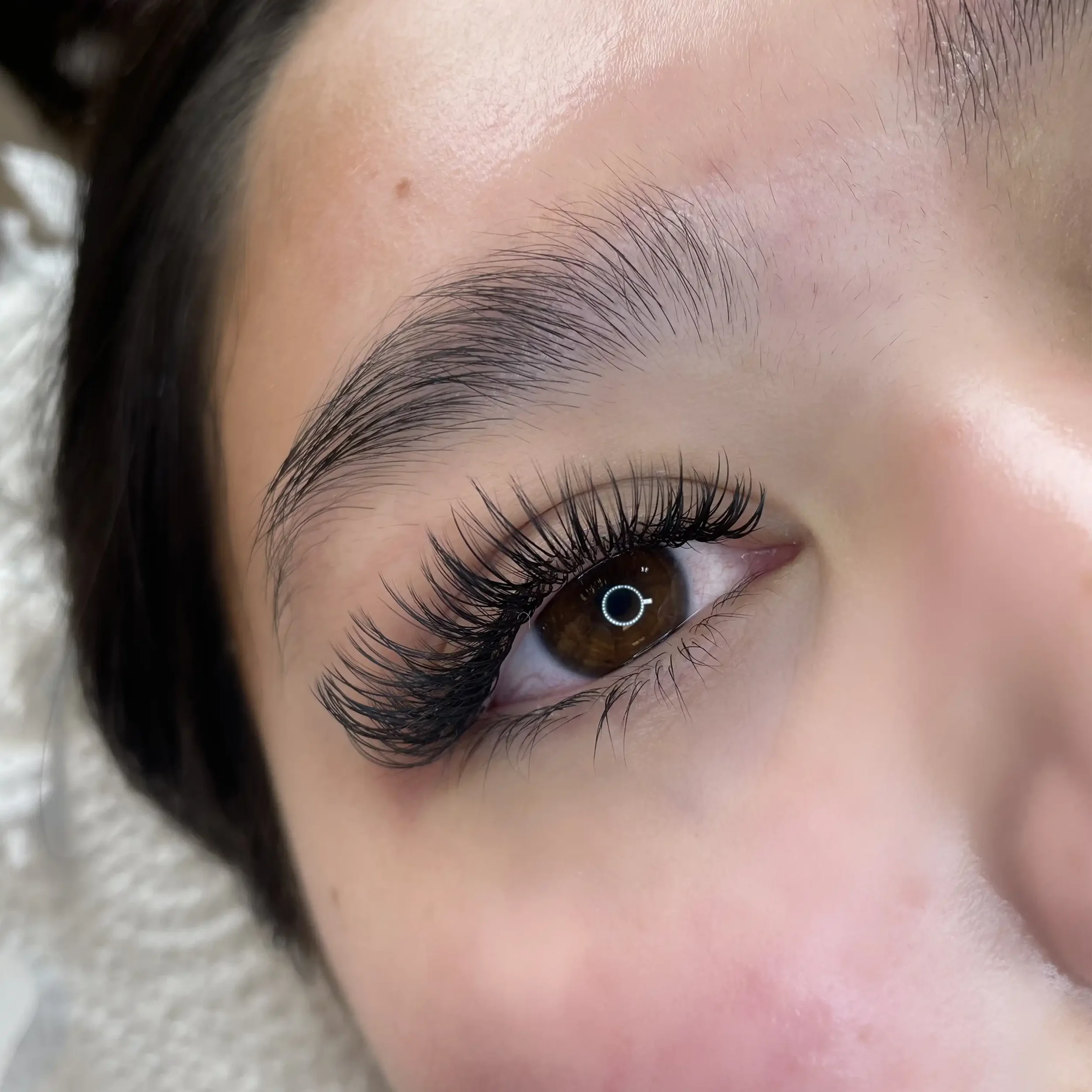 Close-up of a person's eye with long, curled eyelashes and well-defined eyebrows.